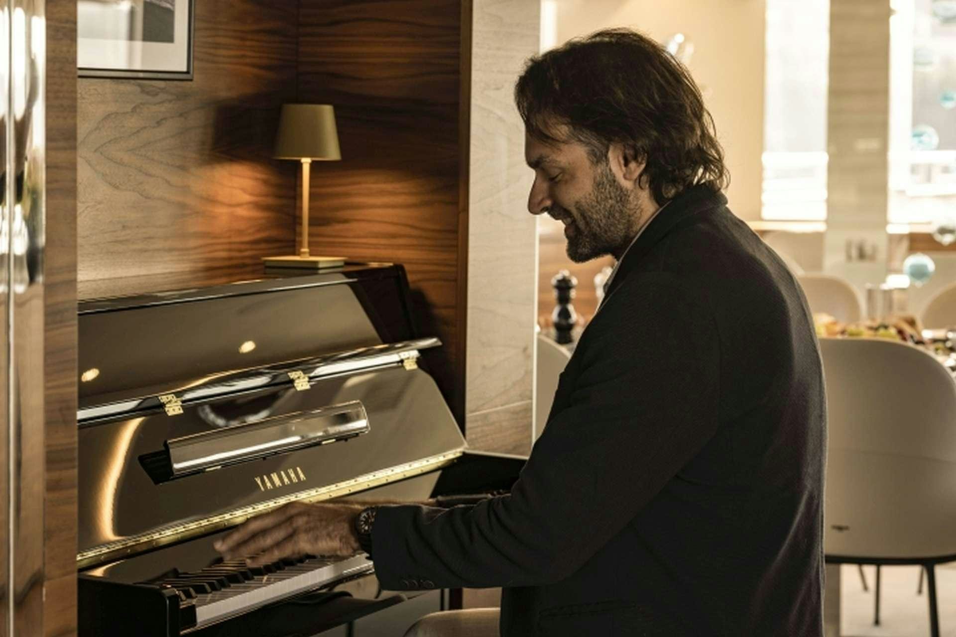 a man playing a piano aboard M/Y ANTHEA Yacht for Charter