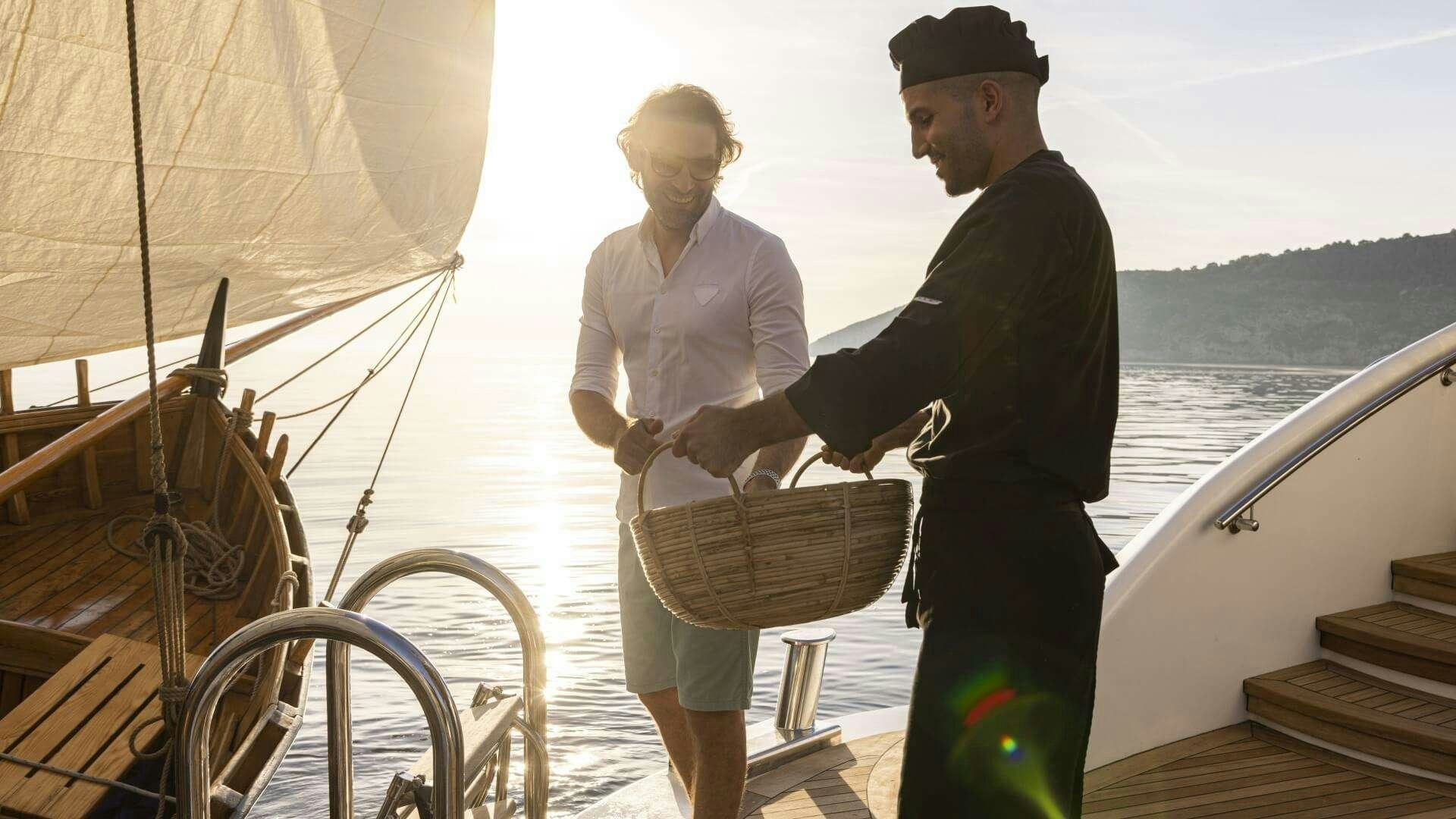a man and a woman standing on a dock next to a boat aboard M/Y ANTHEA Yacht for Charter