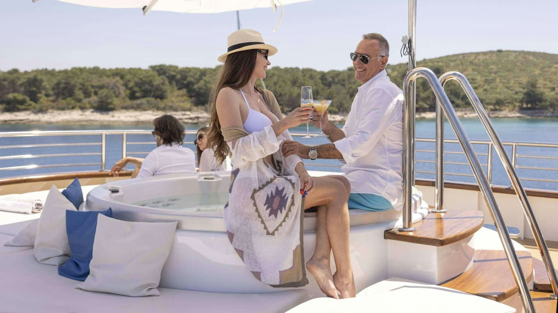 a man and woman sitting on a boat holding wine glasses aboard M/Y ANTHEA Yacht for Charter