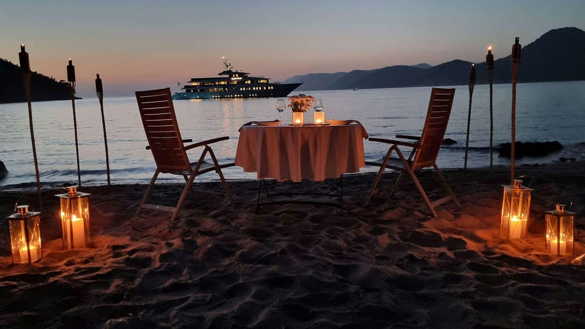 a table with candles on it by a body of water aboard BLACK SWAN Yacht for Charter
