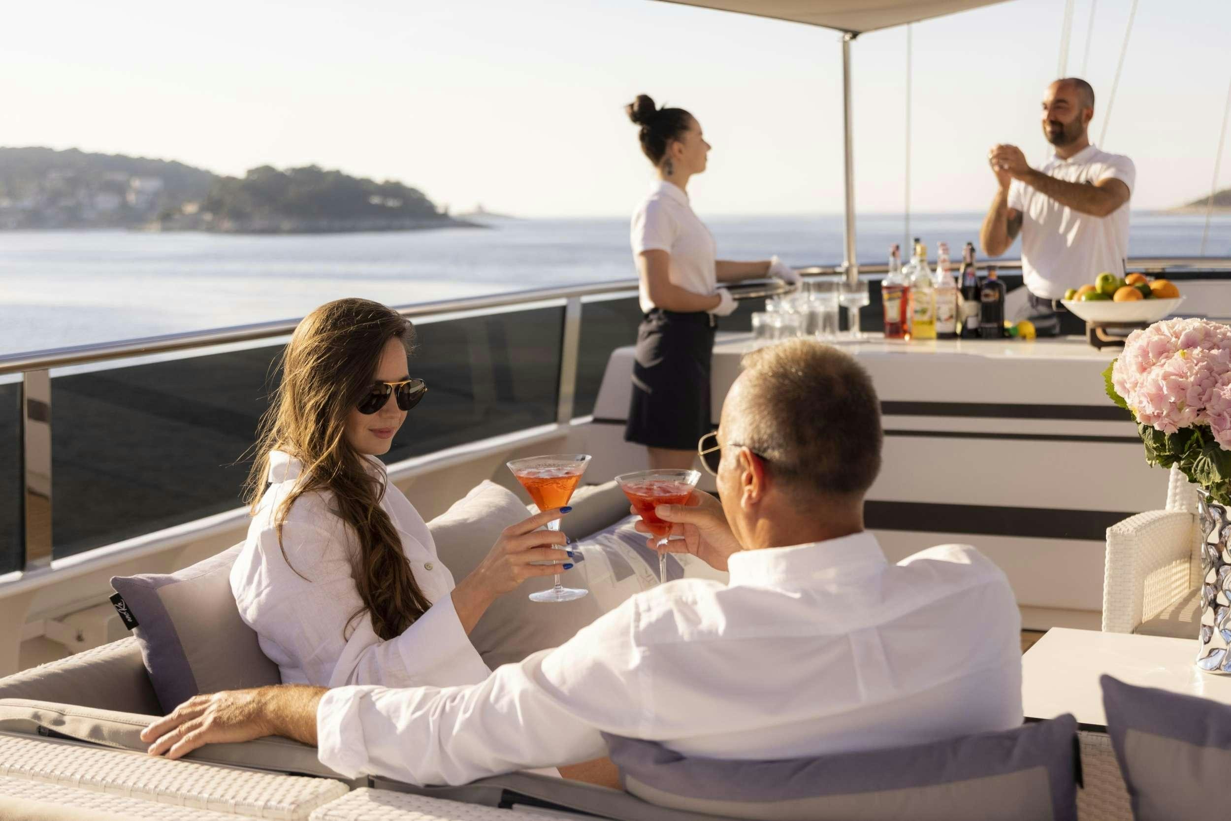 a man and woman sitting at a table with a woman holding a glass of wine aboard M/S AURUM SKY Yacht for Charter