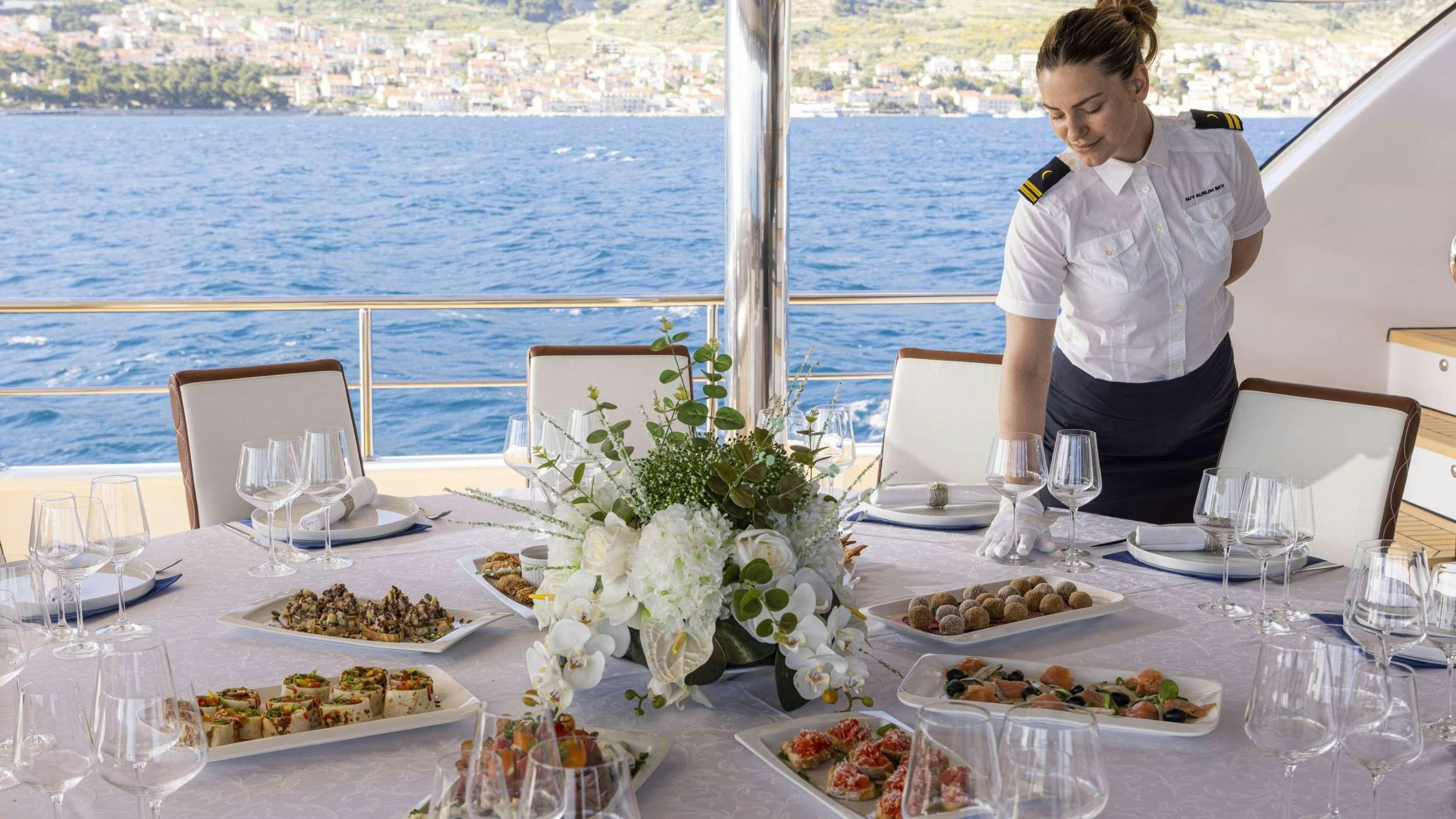 a person sitting at a table with food and flowers on it aboard M/S AURUM SKY Yacht for Charter