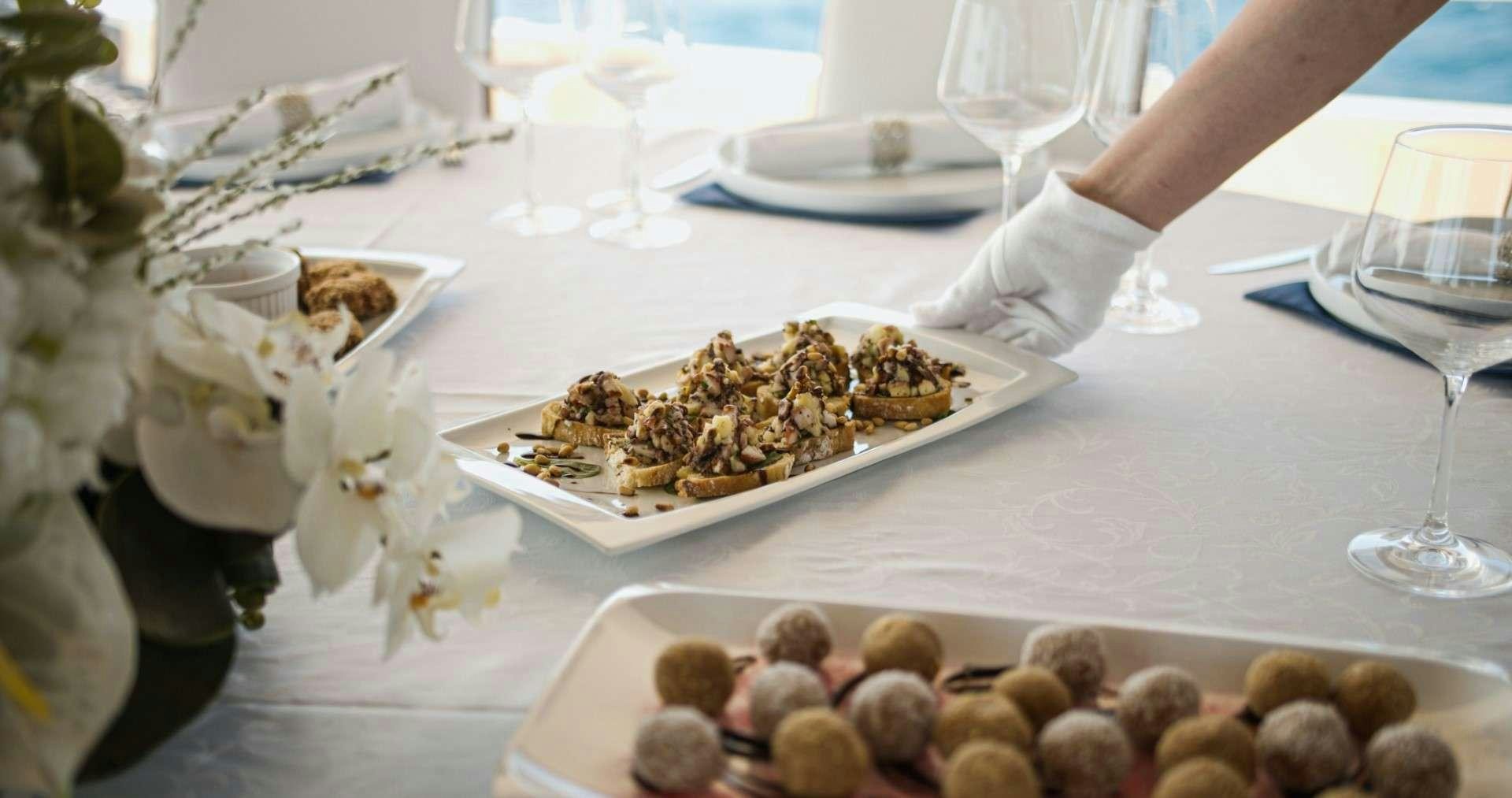 a person pouring a glass of wine into a plate of cookies aboard M/S AURUM SKY Yacht for Charter