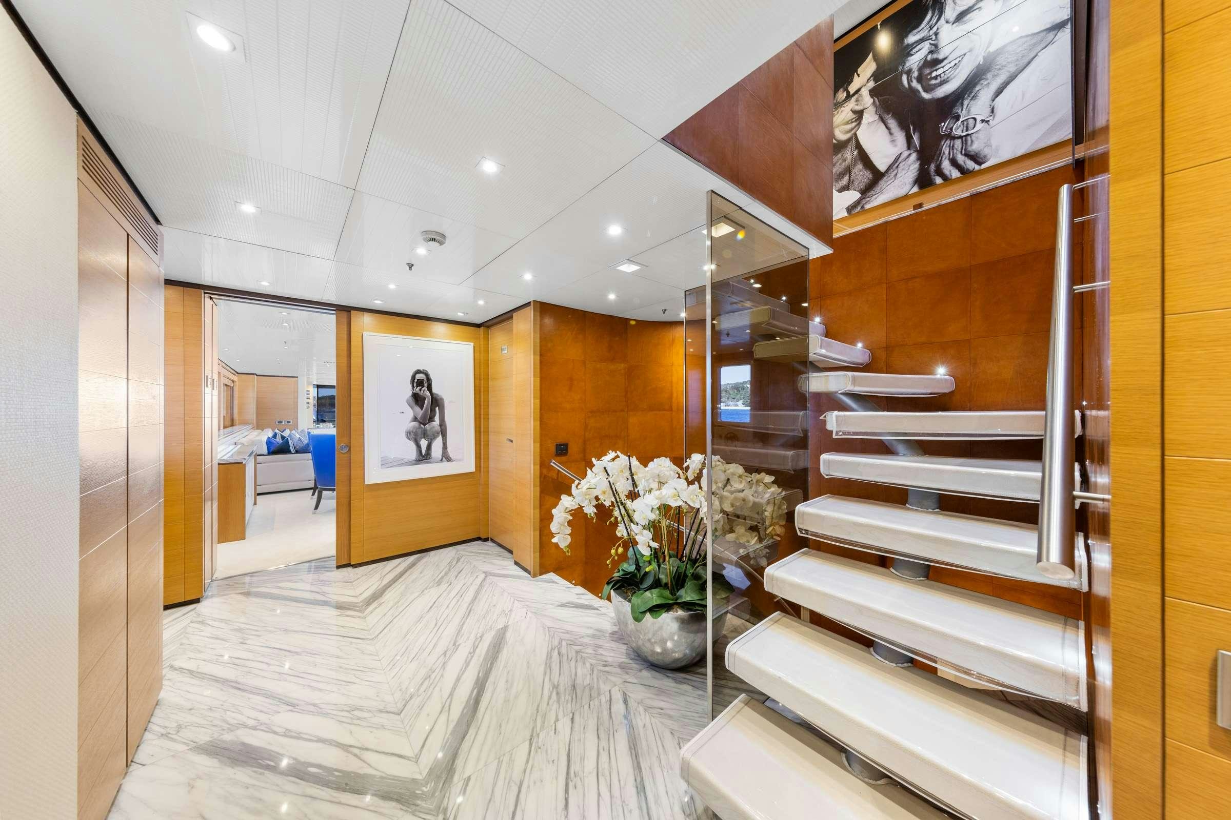 a modern looking room with a large staircase and white flowers aboard MISCHIEF 1 Yacht for Charter