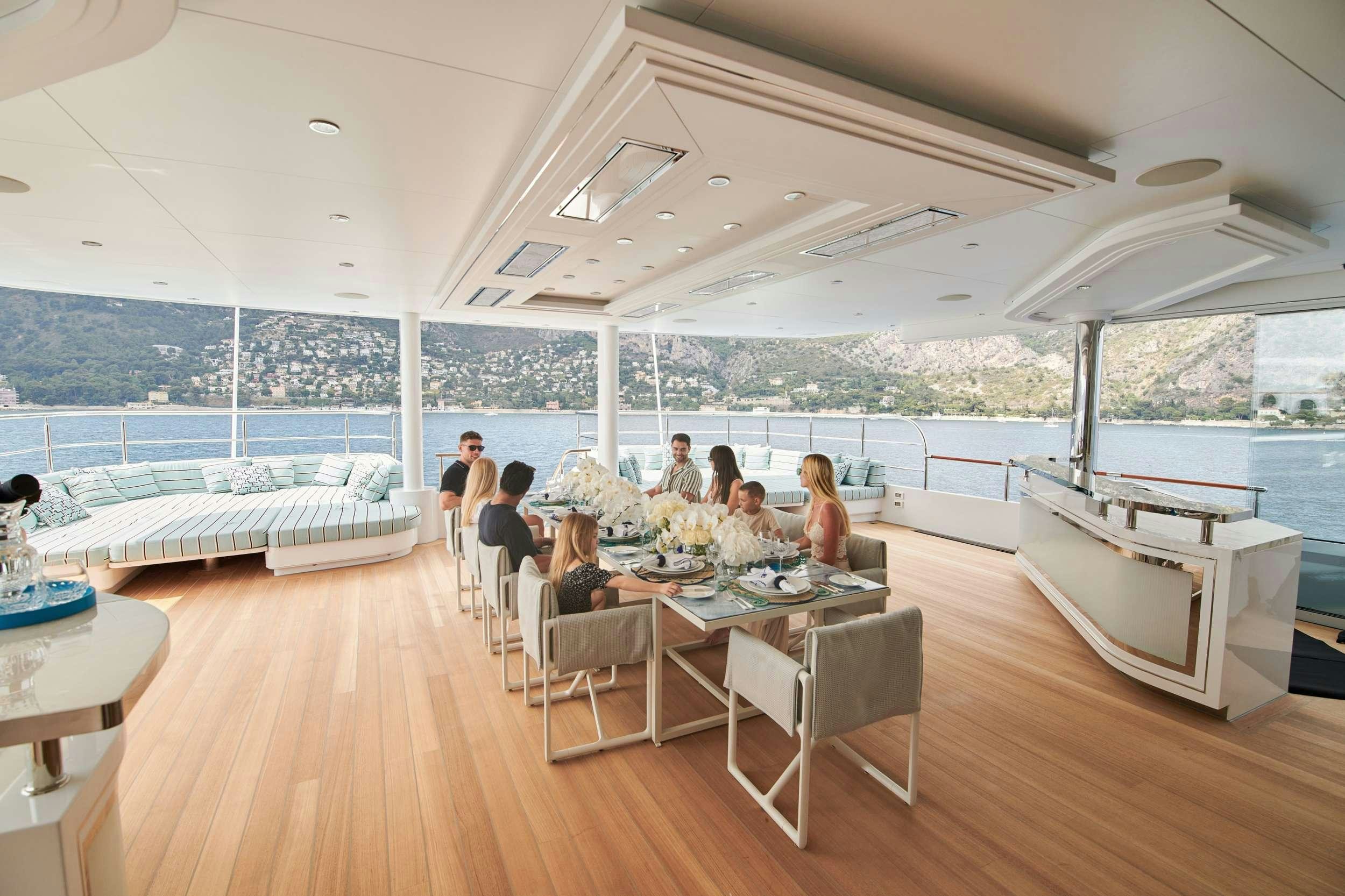 a group of people sitting at a table in a room with a large window aboard CORAL OCEAN Yacht for Charter