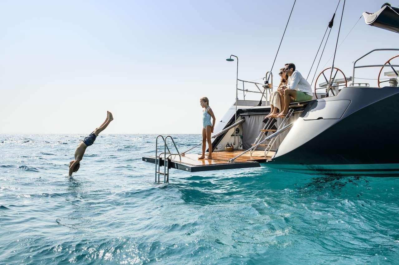 a couple of people jumping off a boat in the water aboard ONYX Yacht for Charter