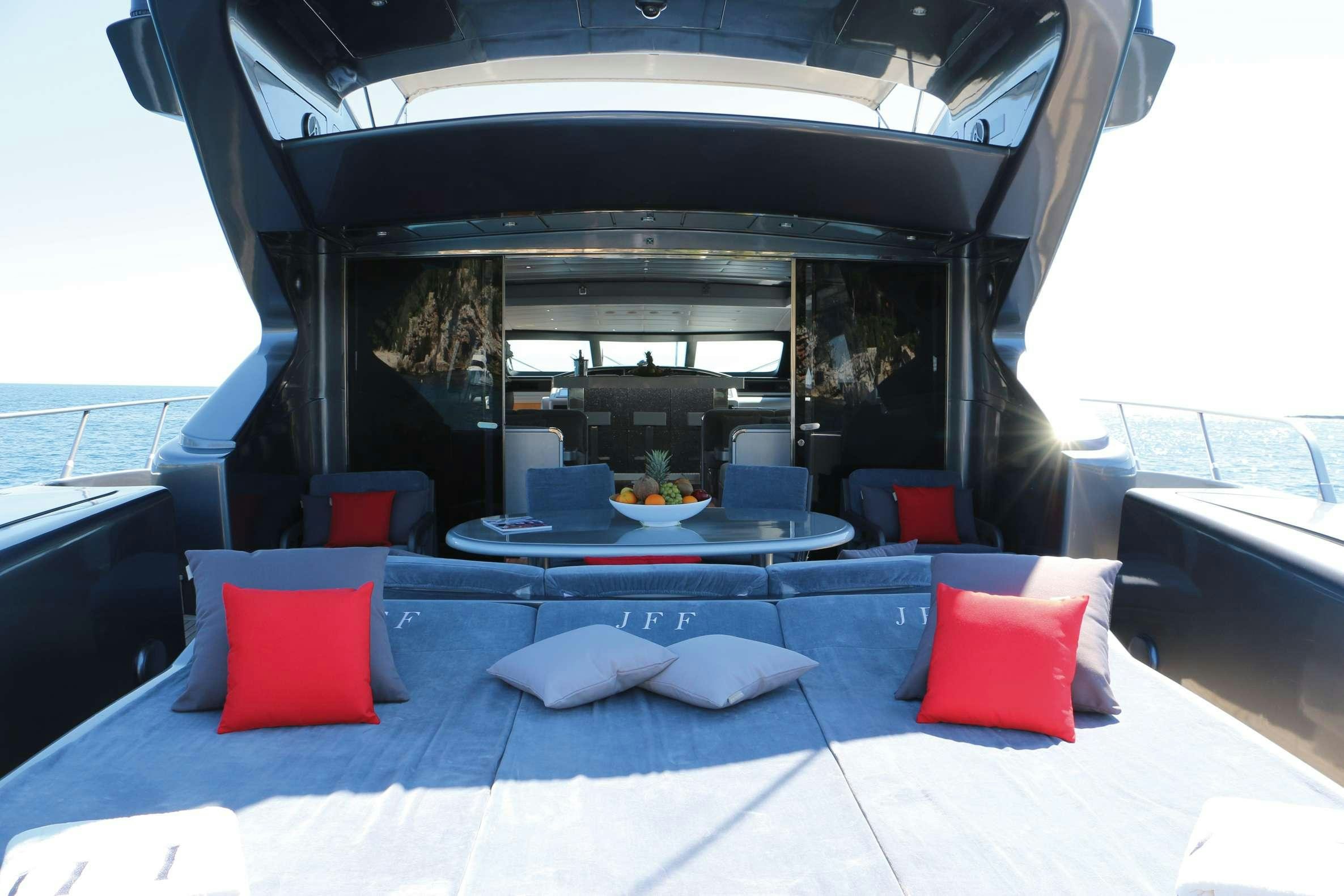 a large lounge area with a large blue lounge chair and red pillows aboard JFF Yacht for Charter