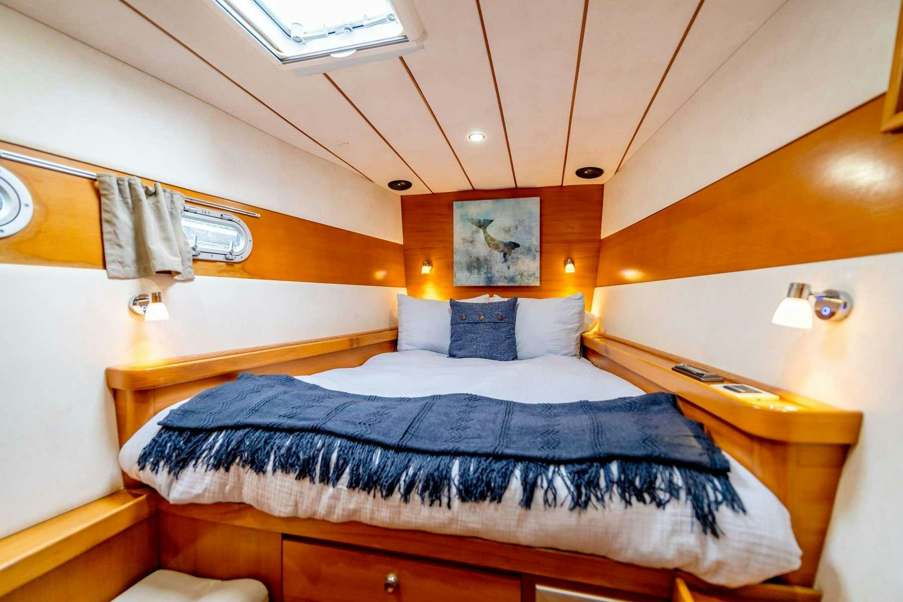 a bed with blue sheets aboard TABULA RASA Yacht for Charter