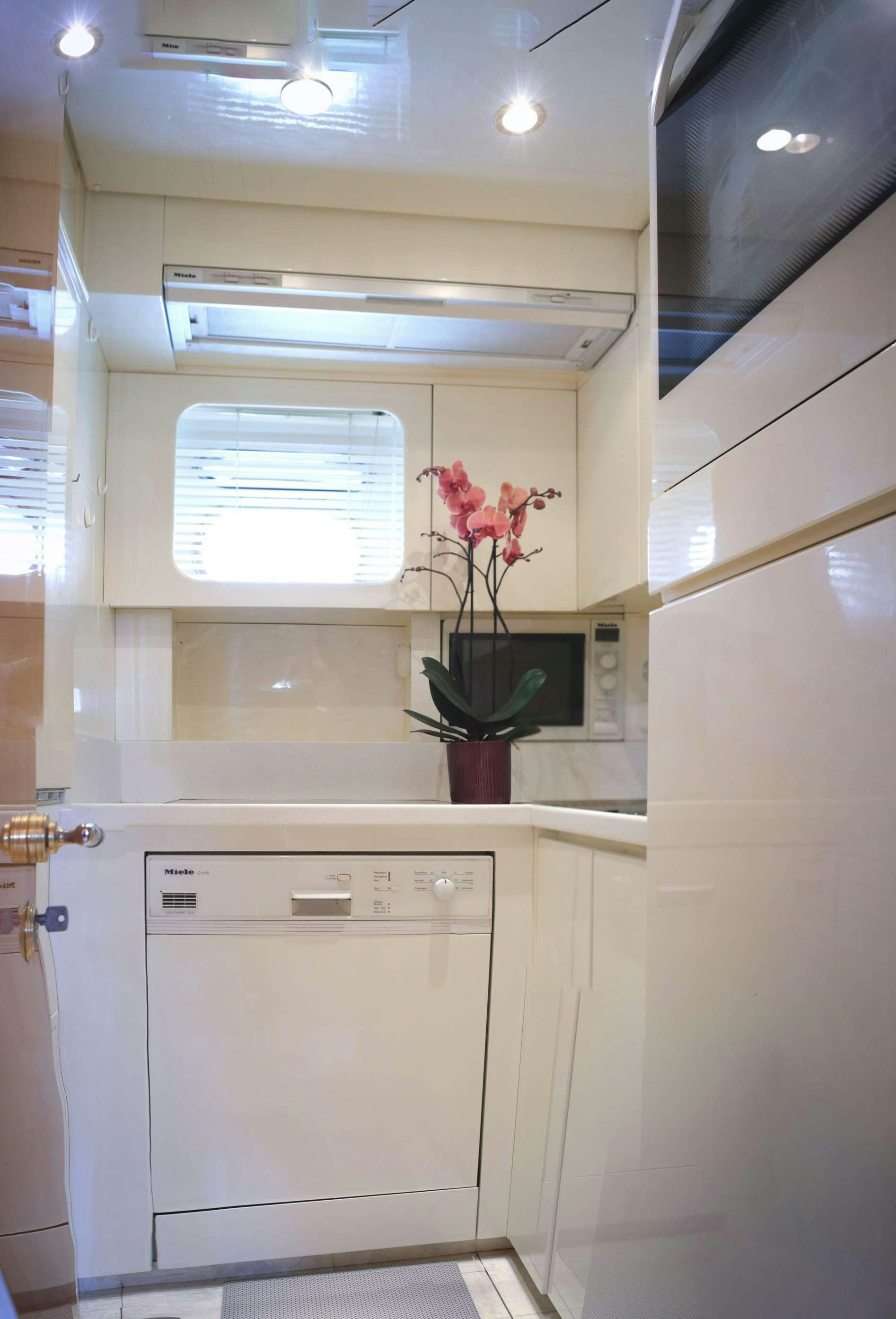 a white kitchen with a plant in a pot on the counter aboard CIKILA Yacht for Charter