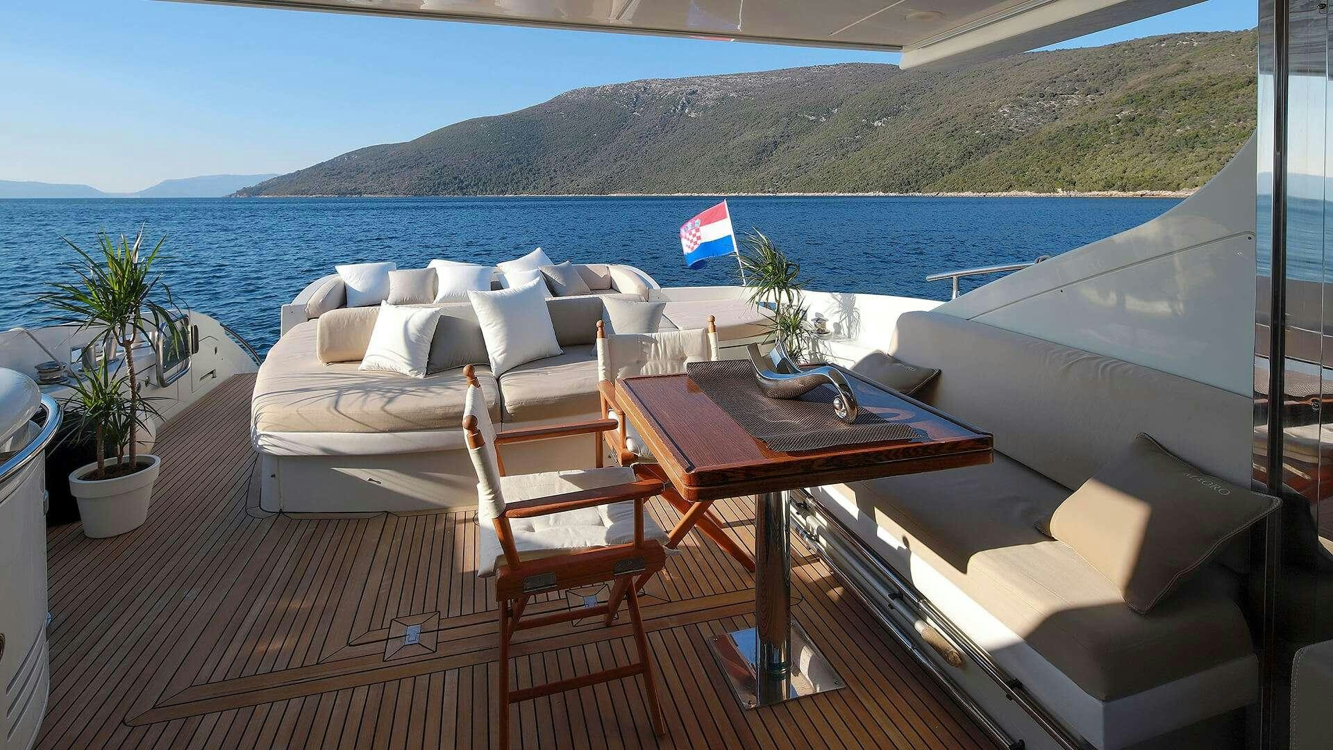 a table and chairs on a deck overlooking a body of water aboard M/Y MAORO Yacht for Charter