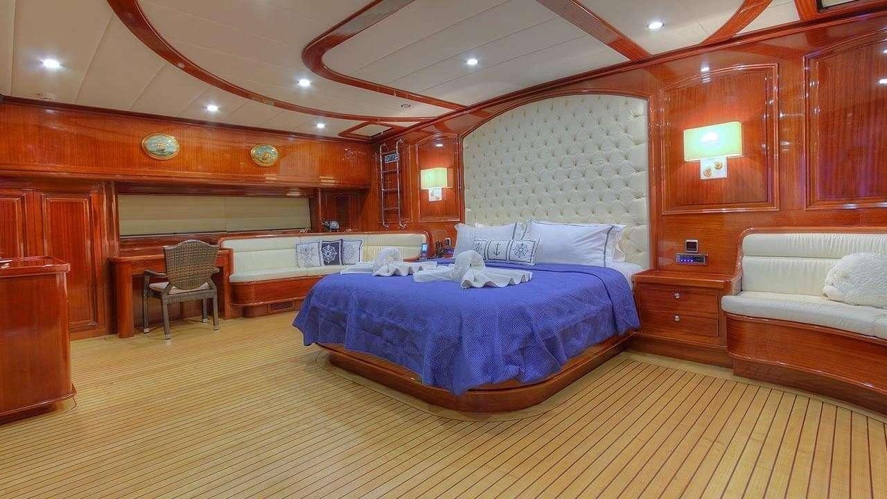 a room with a bed and a chair aboard PERFORMANCE FEE Yacht for Charter