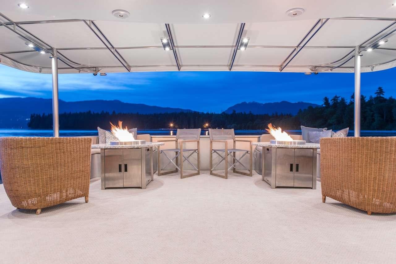 a large outdoor bar with a fire pit and chairs aboard ASCENTE Yacht for Charter