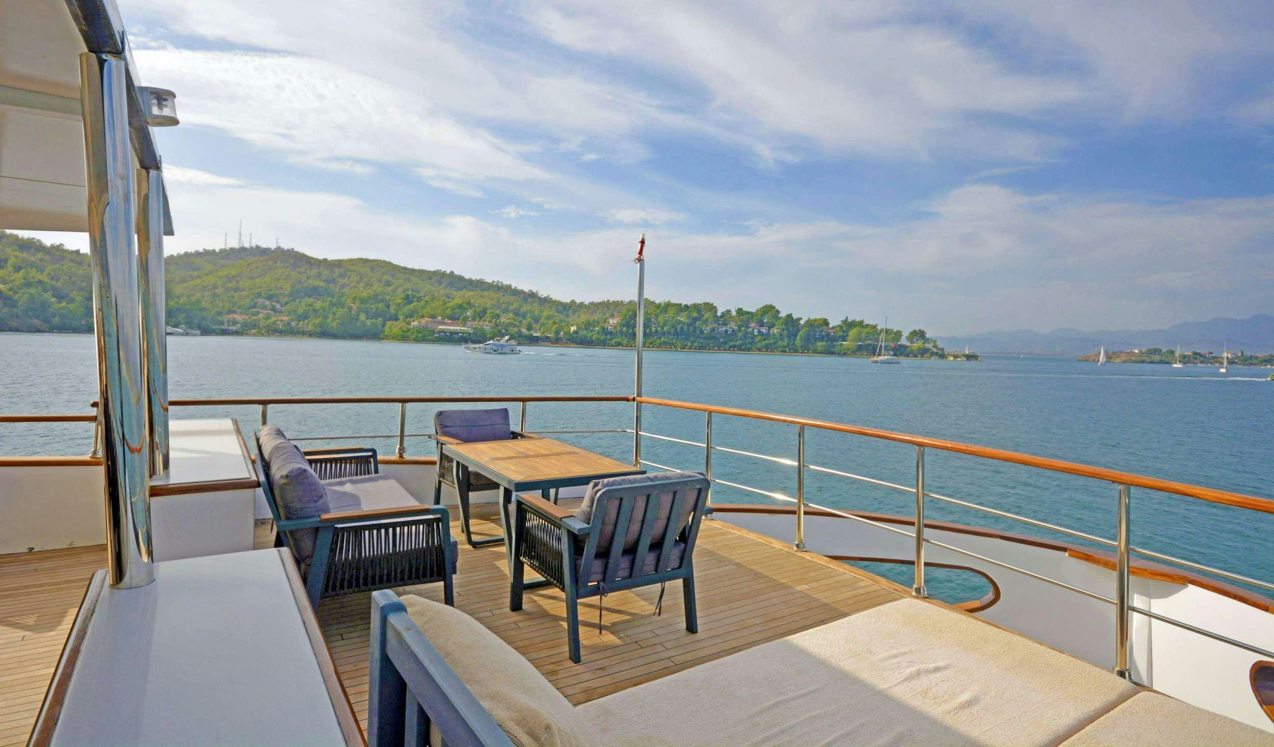 a deck with chairs and tables on it by a body of water aboard NAYK 3 Yacht for Charter