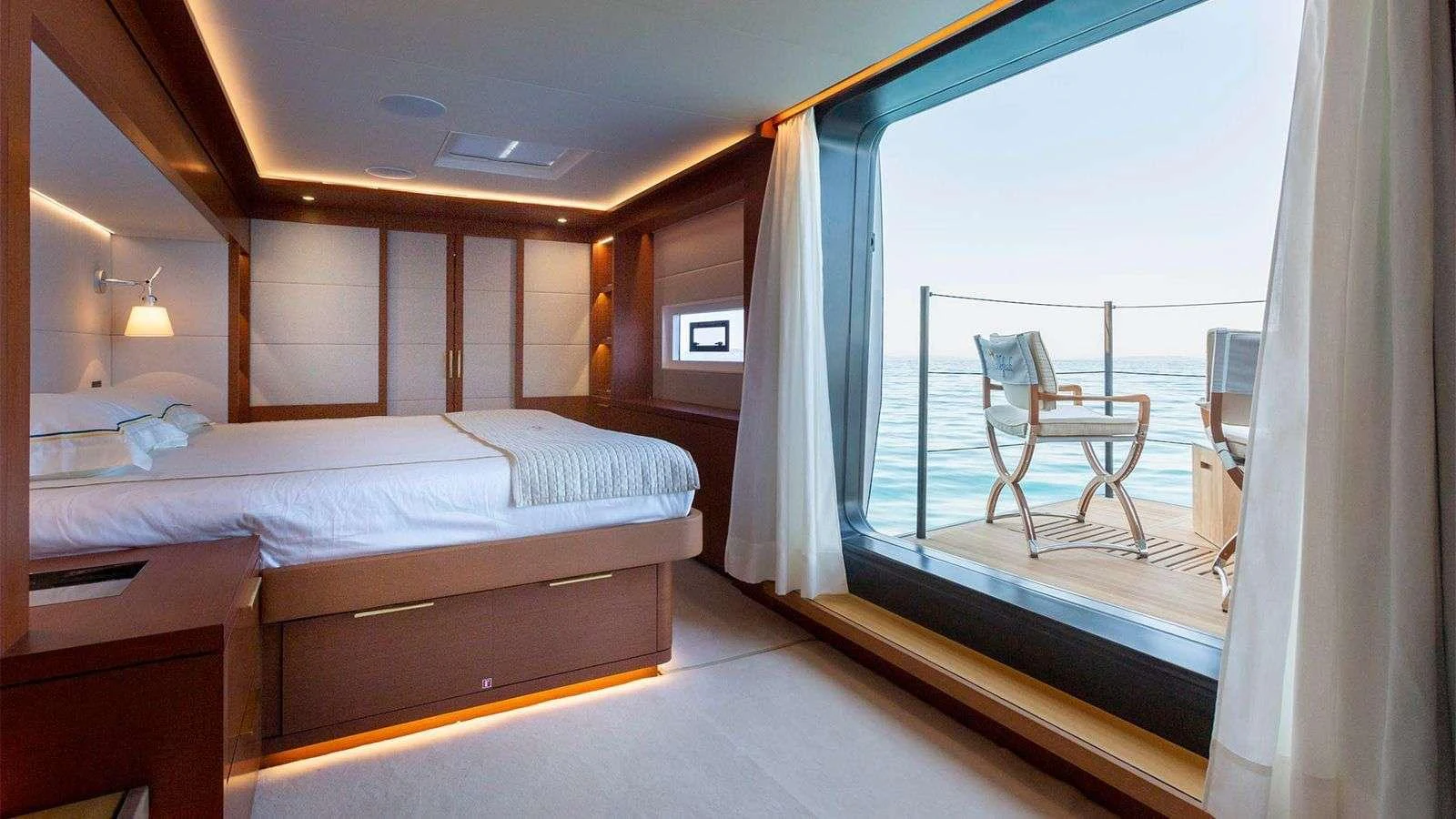 The stateroom features a luxurious bed and a private balcony with stunning ocean views. aboard NEFESH Yacht for Charter