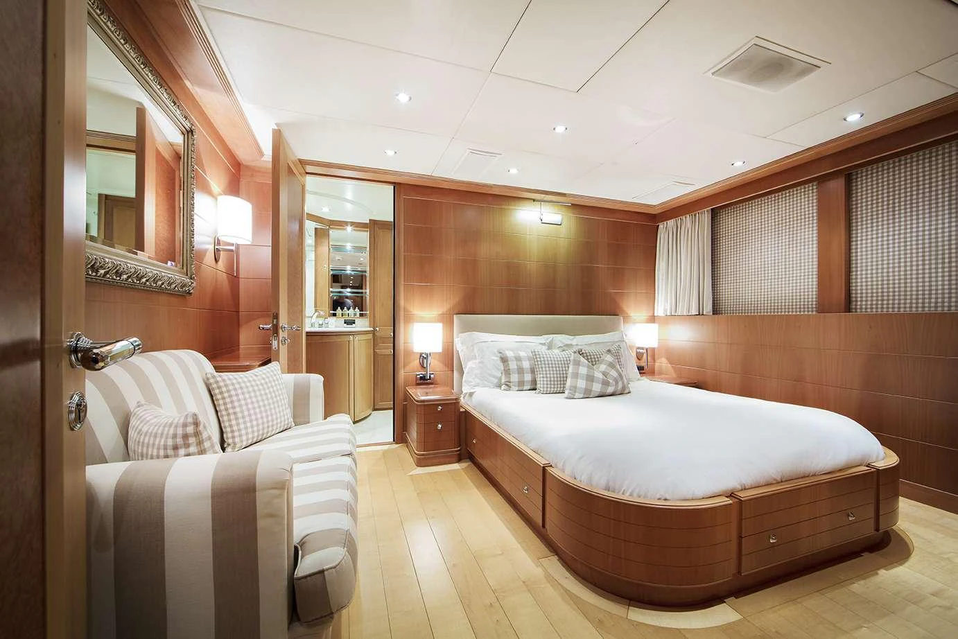 The stateroom features a luxurious bed, elegant wood paneling, and ample natural light. aboard MAC BREW Yacht for Charter