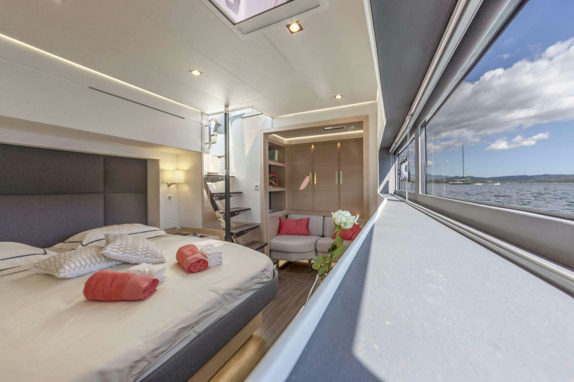 a bed and a chair in a room with a body of water aboard YELLOW Yacht for Charter