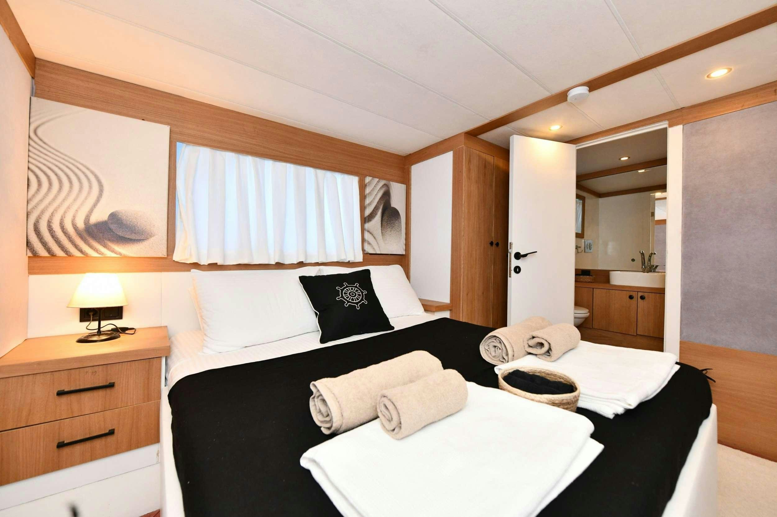 a bed with a black and white bed spread and a white pillow aboard NAYK 2 Yacht for Charter