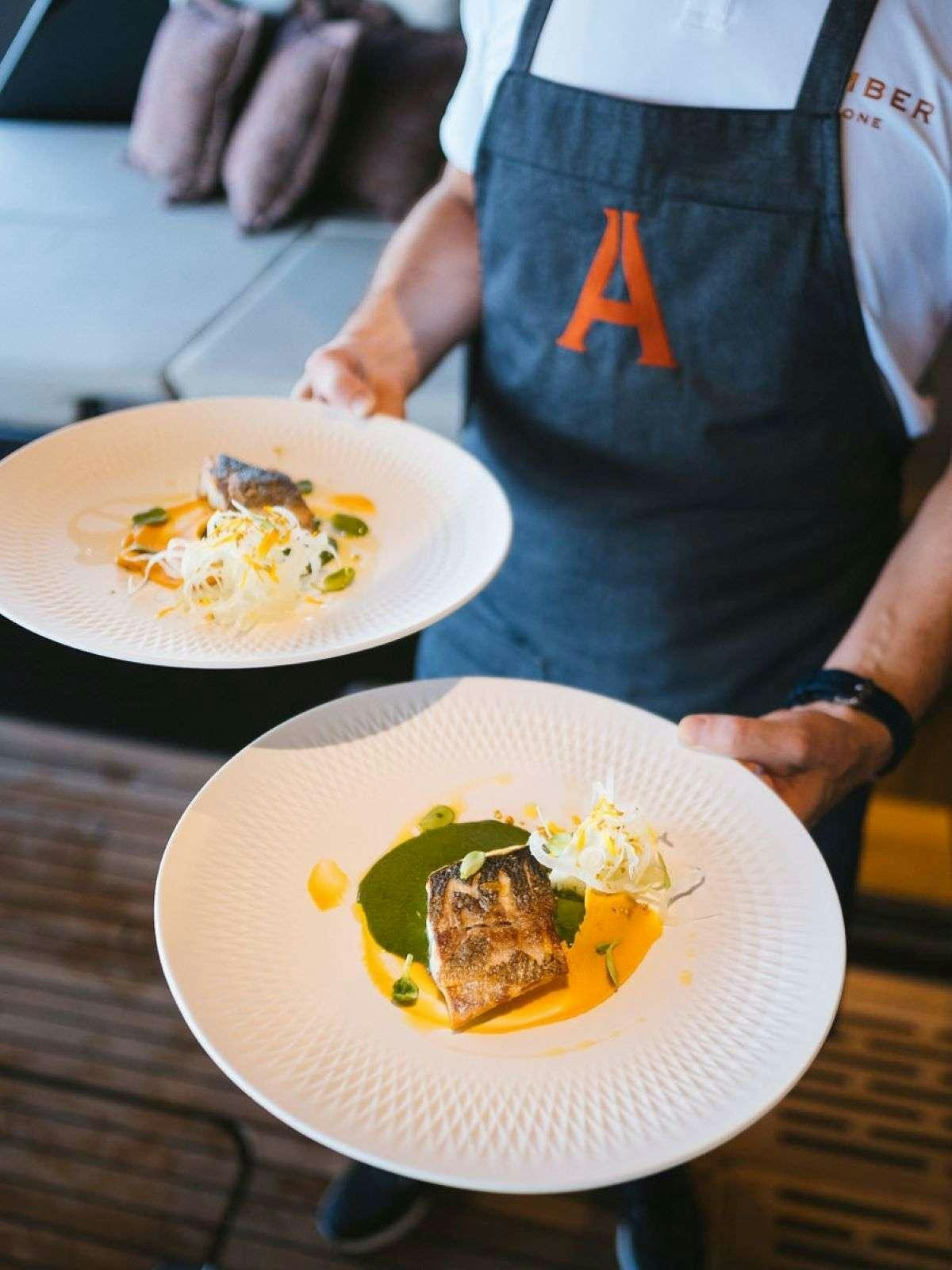 a person holding plates of food aboard AMBER ONE Yacht for Charter