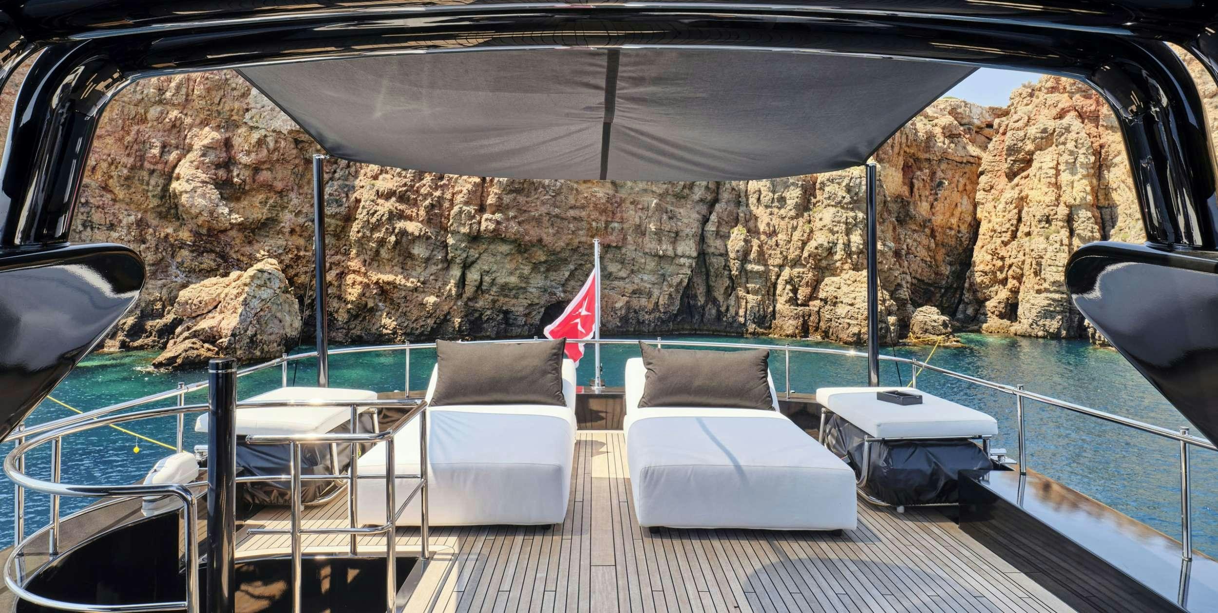 a deck with chairs and a flag aboard ABILITY Yacht for Charter