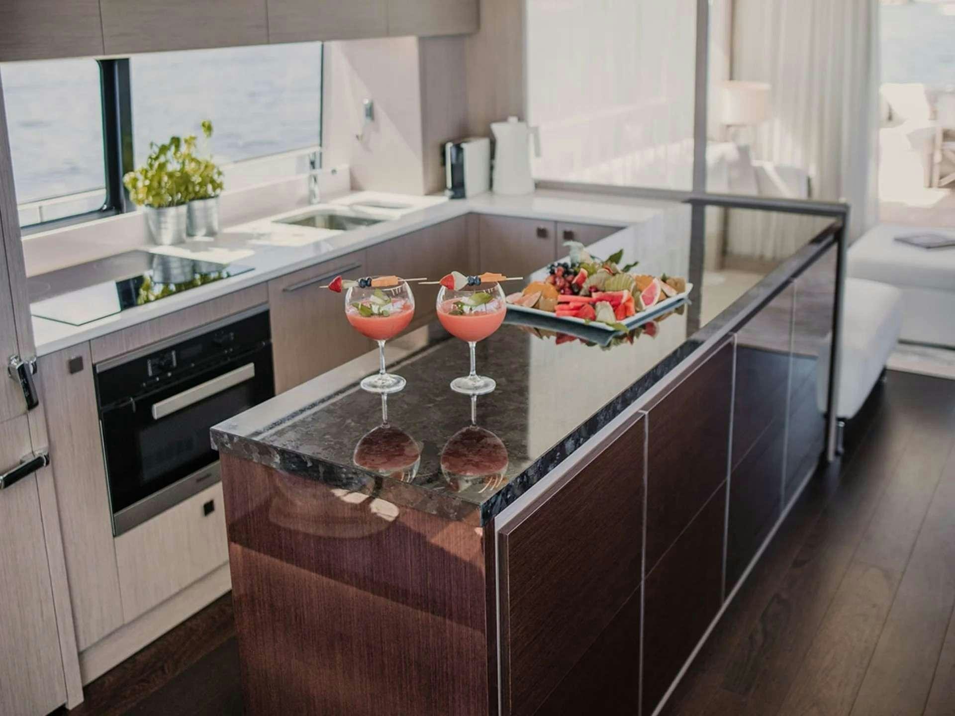 a kitchen with a glass of wine and a bowl of fruit on a counter aboard LADY M Yacht for Charter