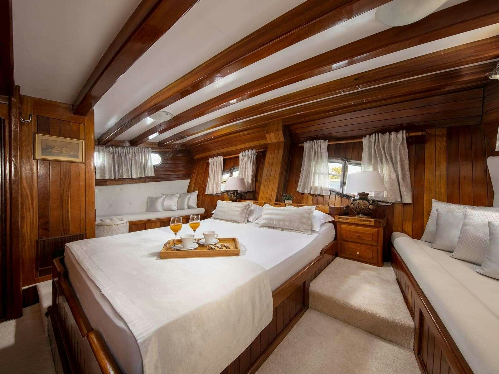 a room with a bed and a table with a glass window aboard GULET ANDI STAR Yacht for Charter