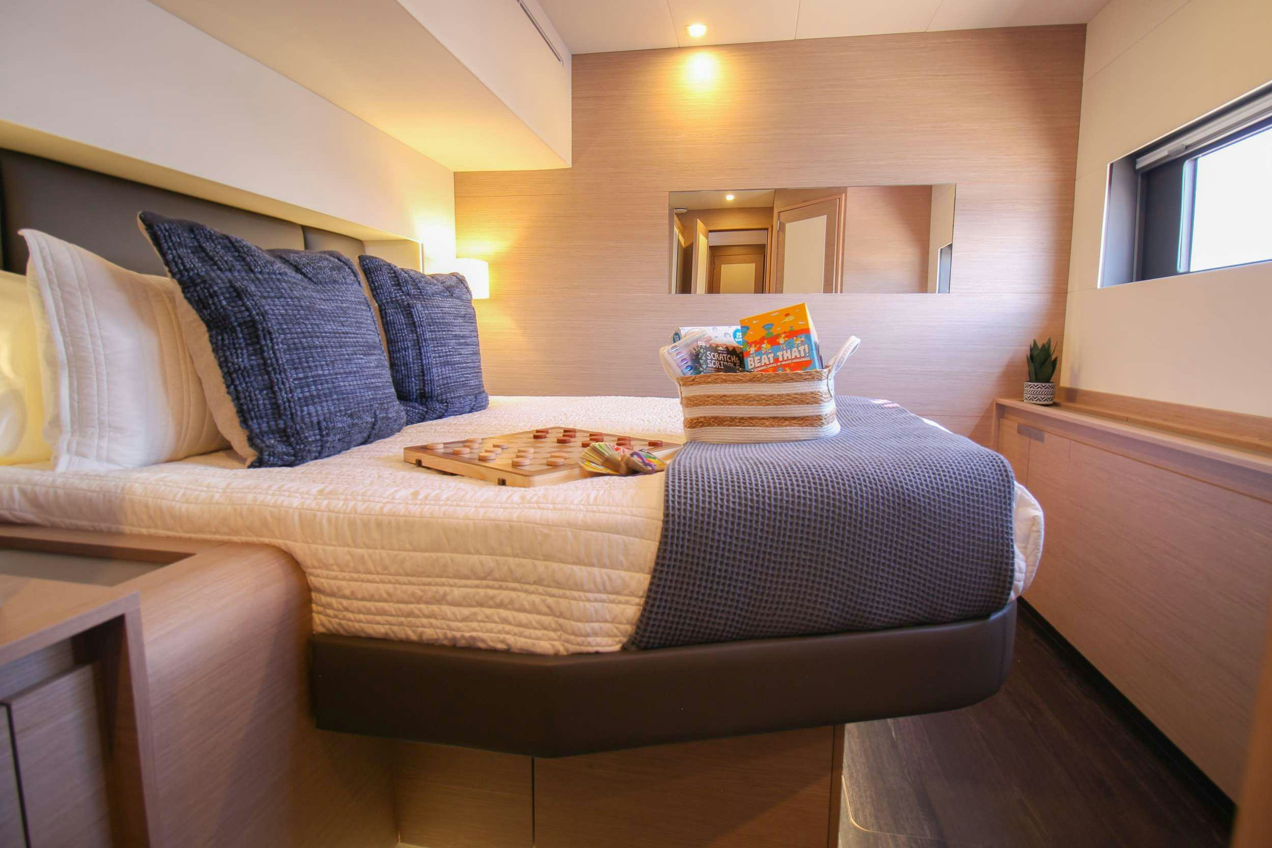 a bed with a blue and white comforter and pillows aboard PRINCESS MILA Yacht for Charter