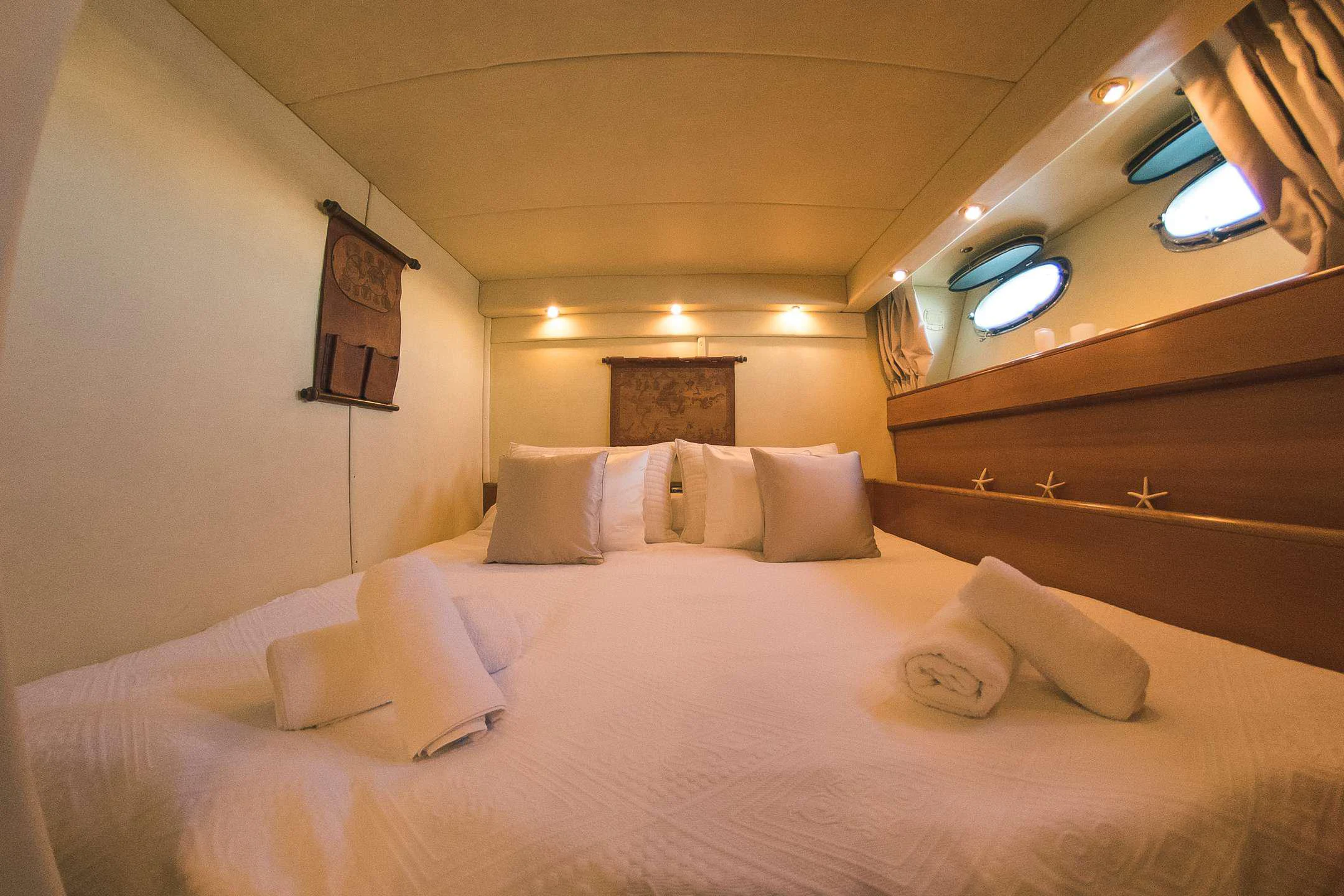 a bed with white sheets and pillows aboard TEMPTATION Yacht for Charter