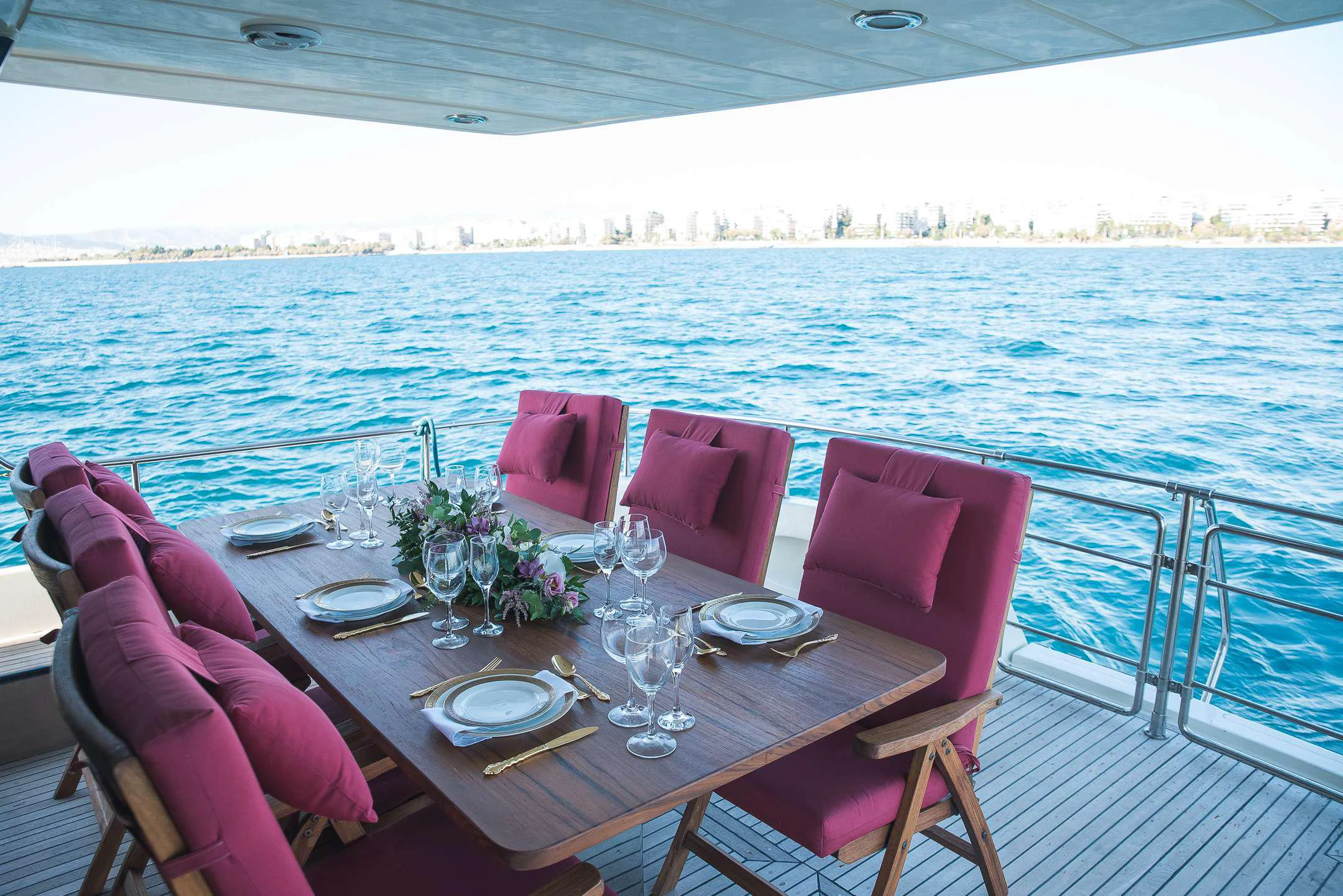a table set for a dinner on a deck overlooking a large body of water aboard TEMPTATION Yacht for Charter