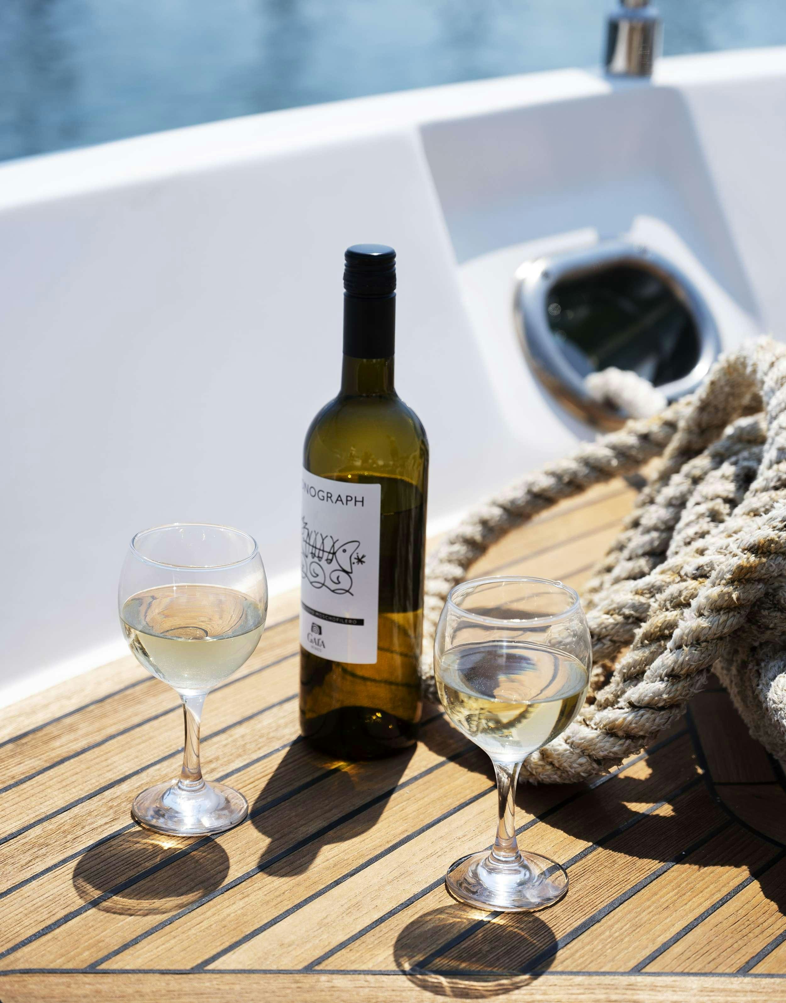 a bottle of champagne next to a glass of champagne aboard VENTUS 21 Yacht for Charter