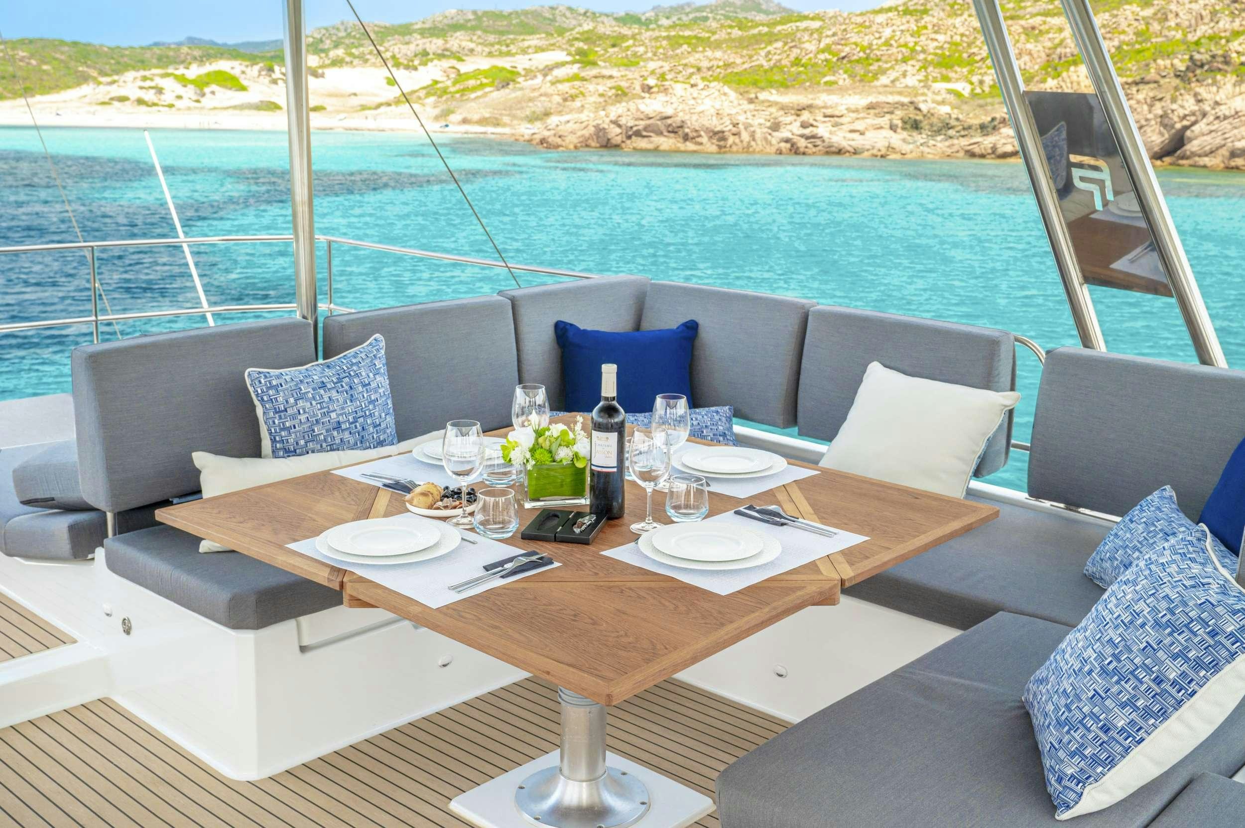 a table with a wine bottle and a view of the ocean aboard SEMPER FIDELIS Yacht for Charter