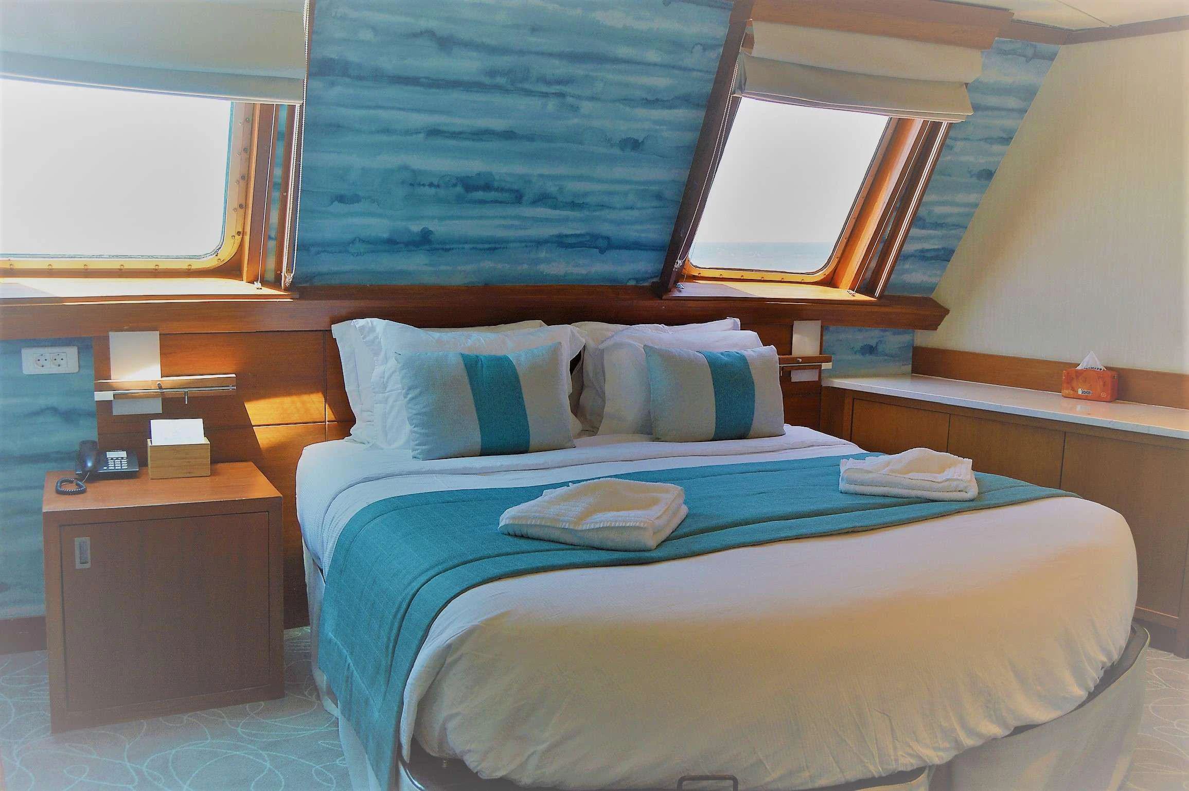 a bed with a blue sheet aboard ELYSIUM Yacht for Charter
