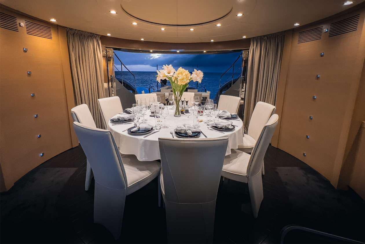 a dining room table with white chairs aboard YCM 120 Yacht for Charter