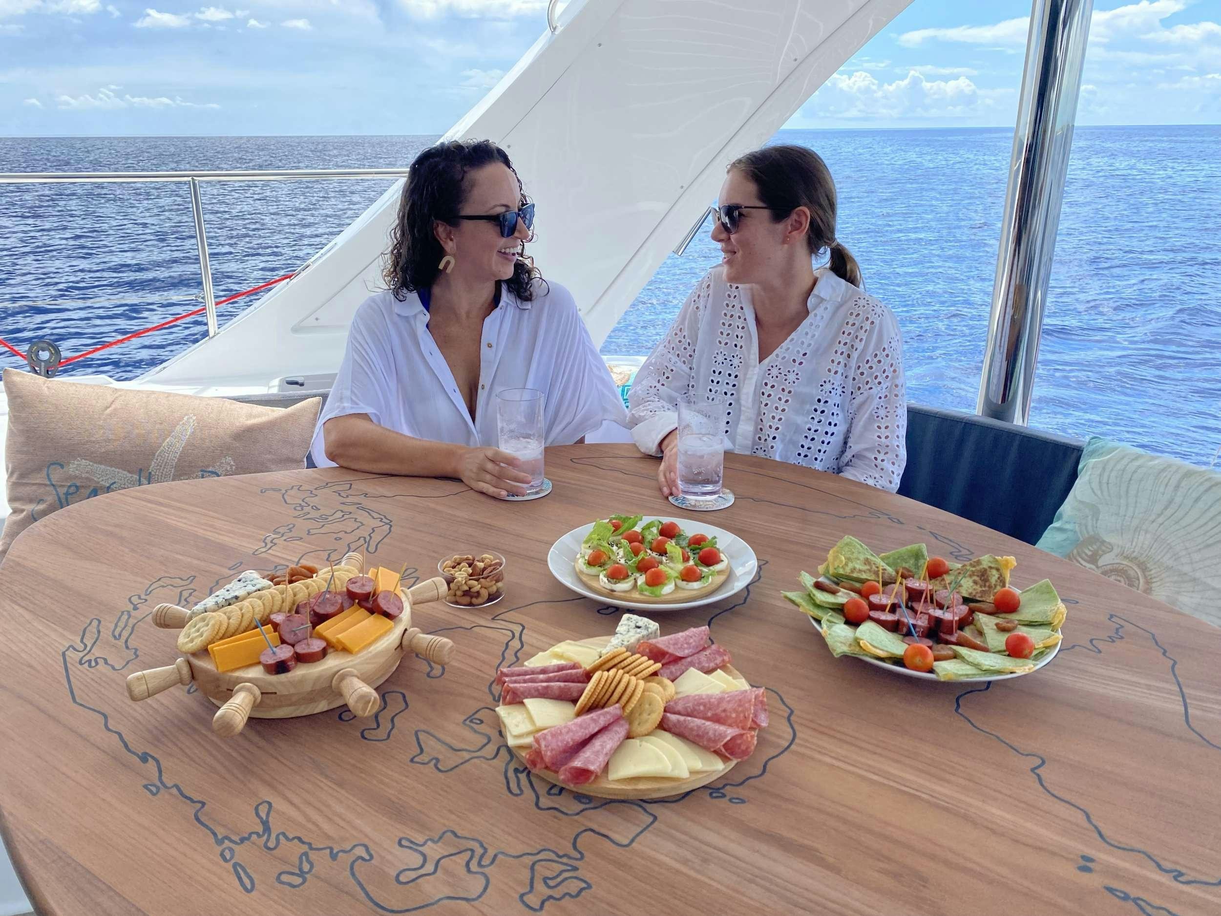 a couple of women sitting at a table with food on it aboard WEIHAII Yacht for Charter