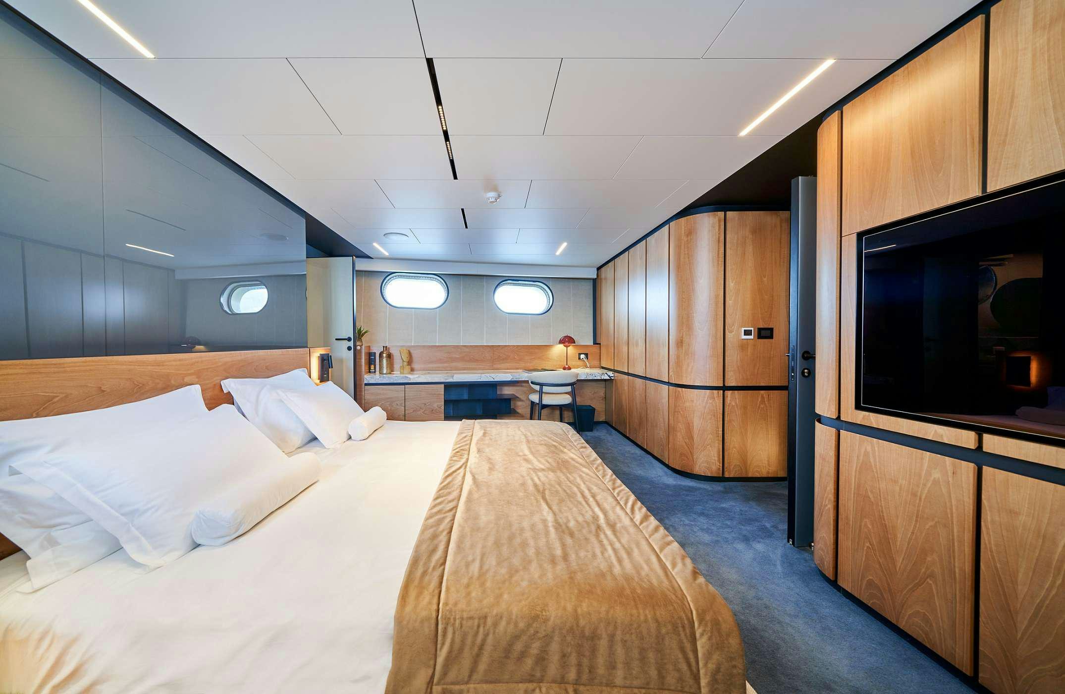 a room with a bed and a television aboard MARALLURE Yacht for Charter