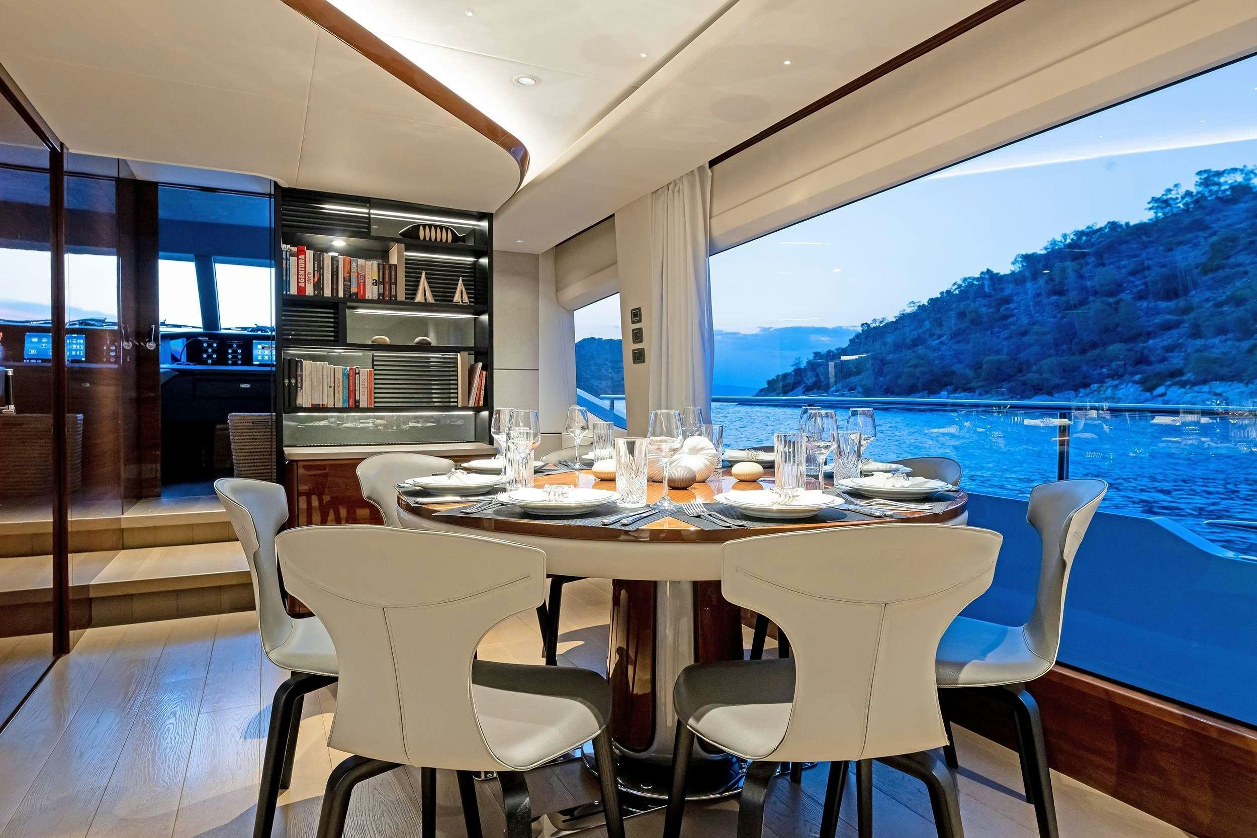 a dining table with a view of the water and mountains in the background aboard VISTA Yacht for Charter