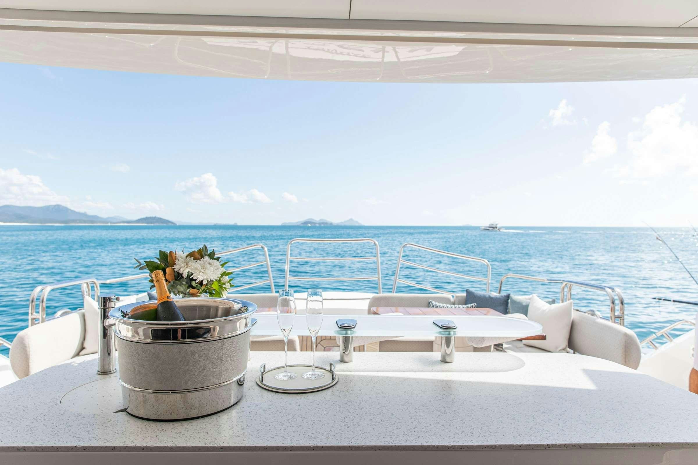 a table with glasses and flowers on it by a body of water aboard RASCAL Yacht for Charter