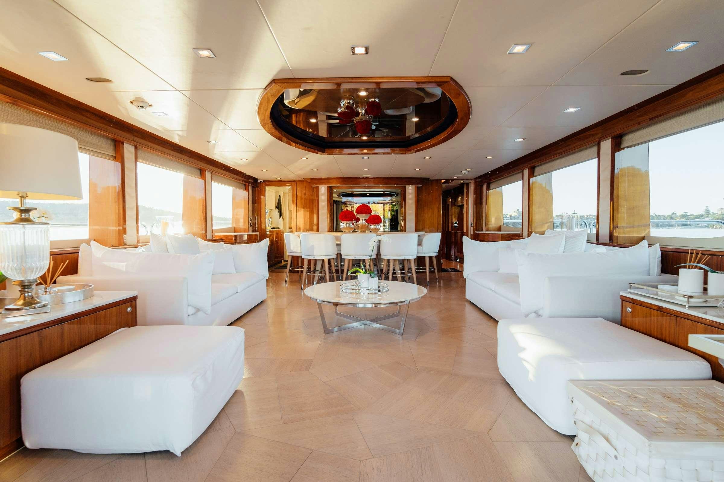 a large living room with white couches and a table aboard CHAOS Yacht for Charter