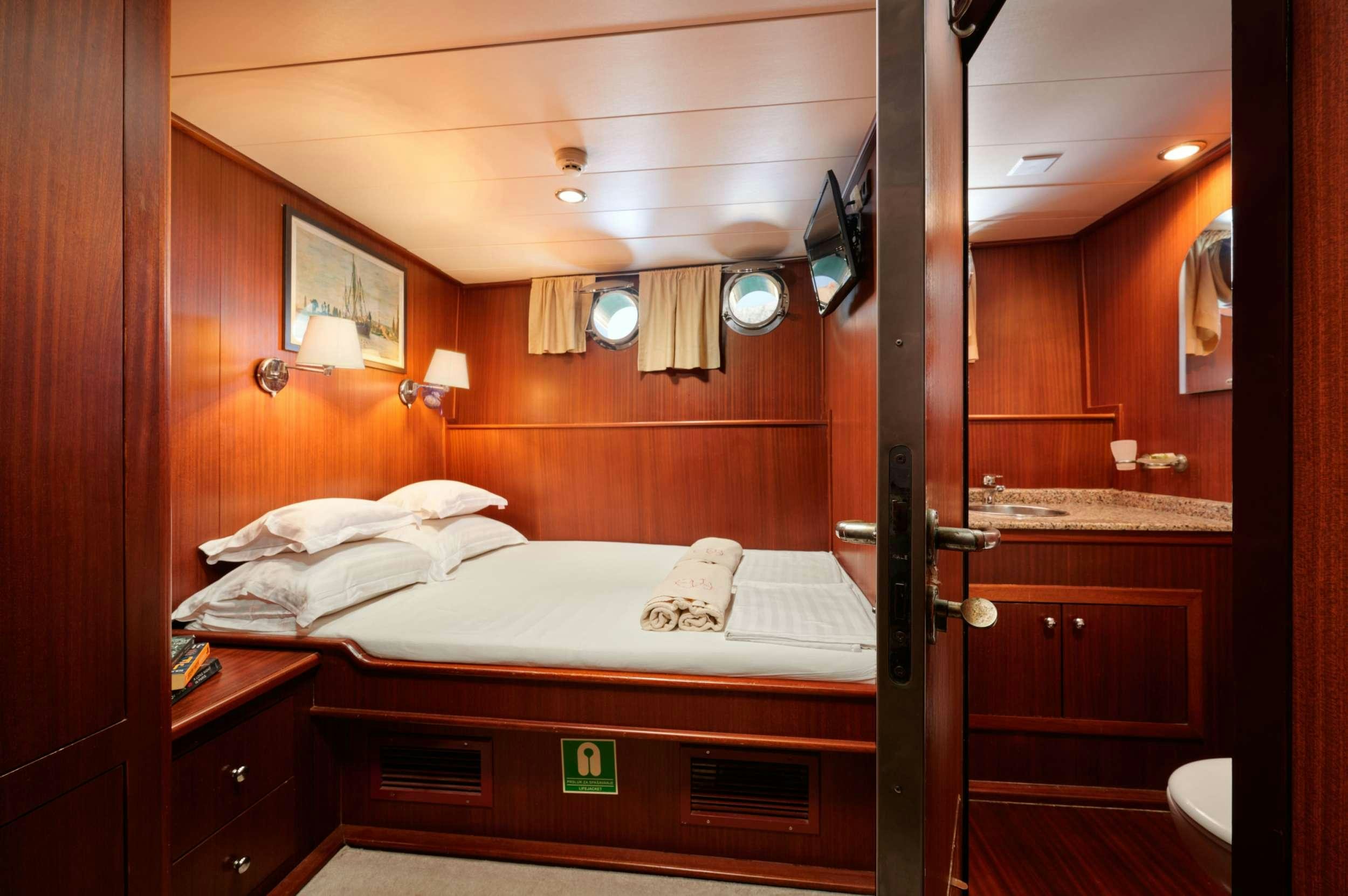 a room with a bed and a mirror aboard QUEEN OF ADRIATIC Yacht for Charter
