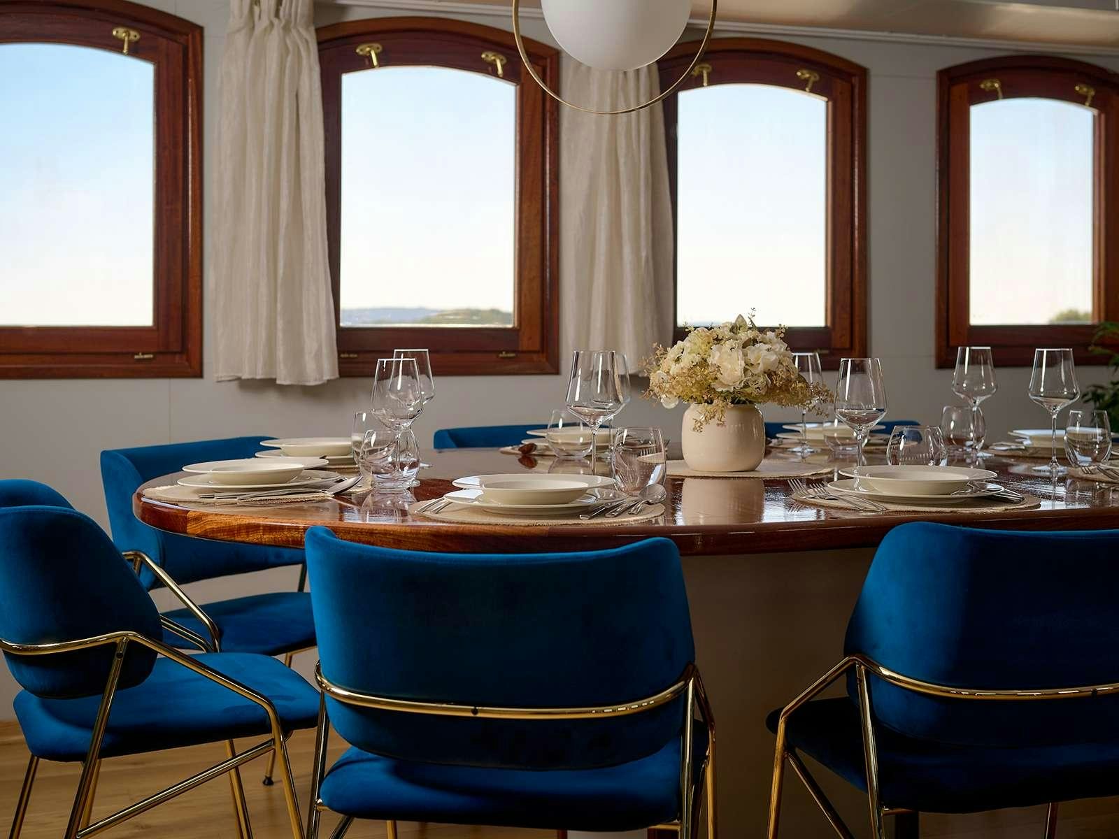 a dining table with blue chairs aboard BELLEZZA Yacht for Charter