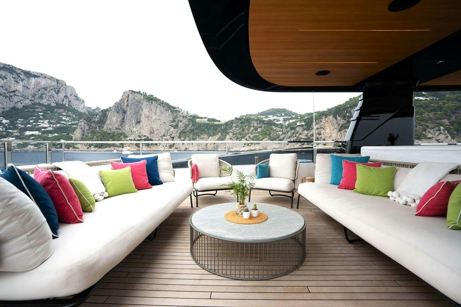 a room with a couch and a table with pillows and a view of mountains aboard HALARA Yacht for Charter