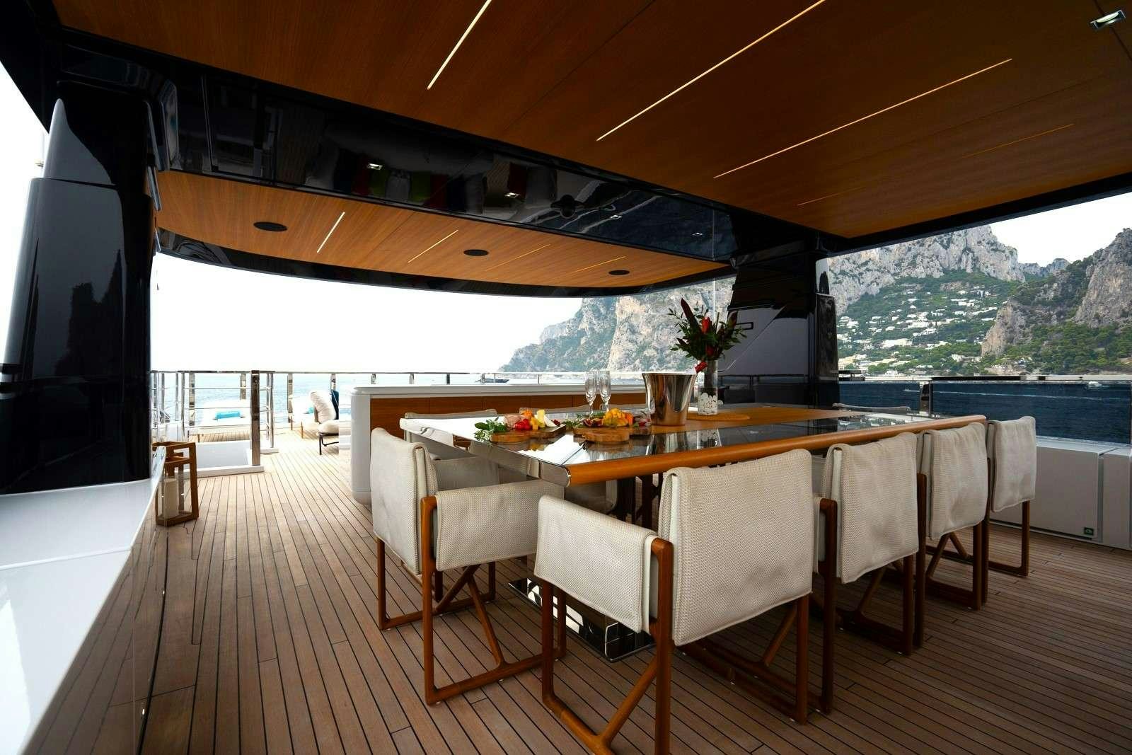 a wood table with white chairs and a large window overlooking a body of water aboard HALARA Yacht for Charter