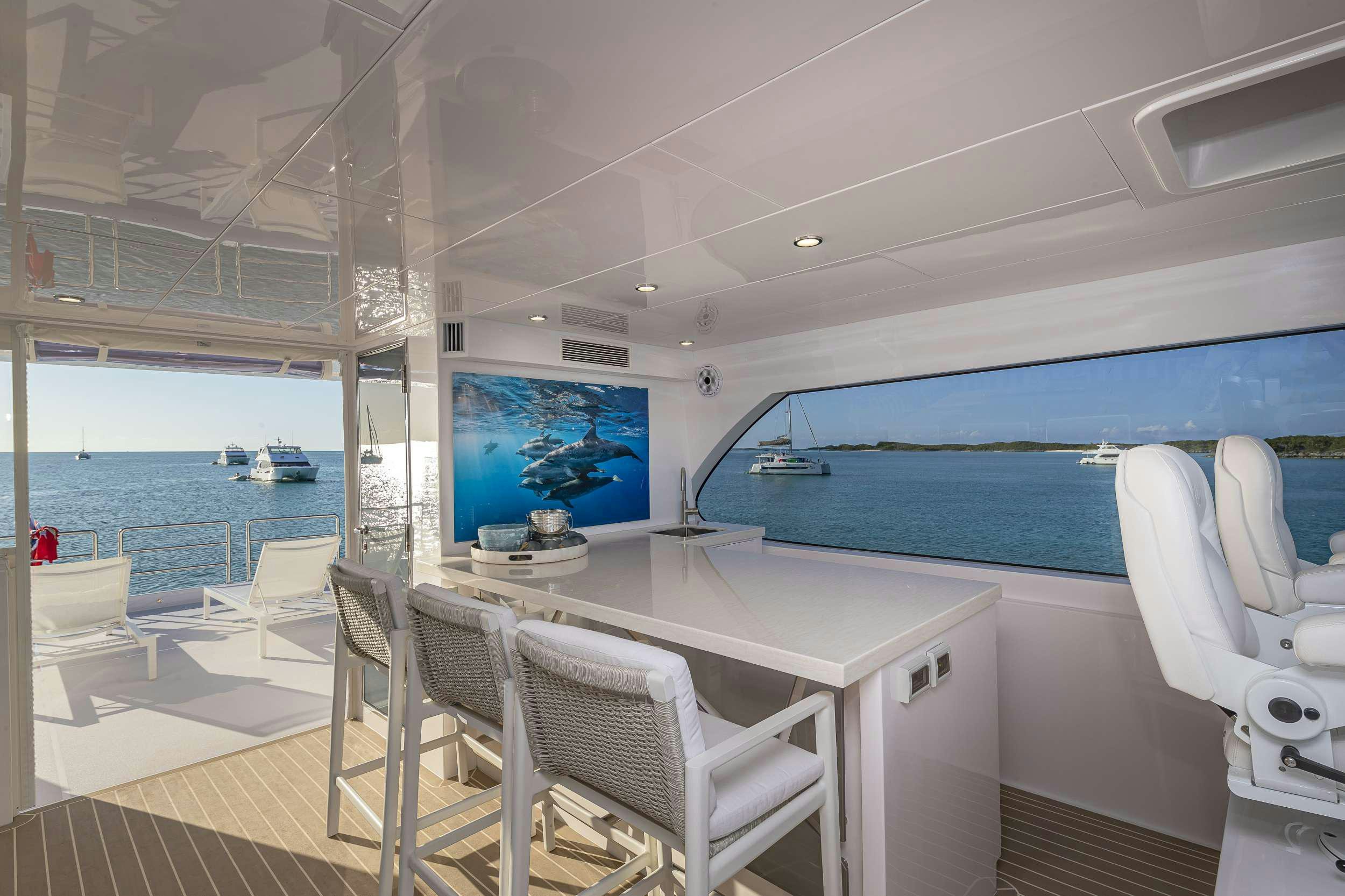 a room with a table chairs and a view of the water aboard OMAKASE Yacht for Charter