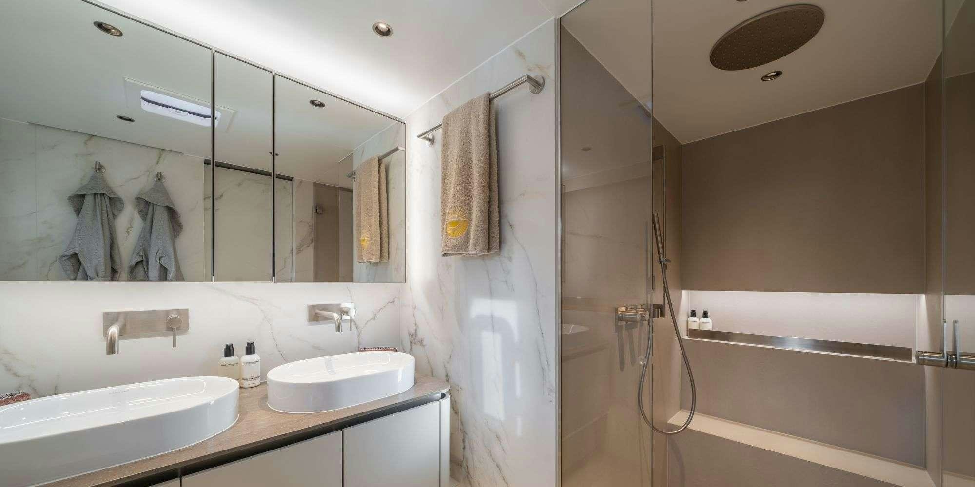 a bathroom with a shower sink and a mirror aboard APOLLO 99 Yacht for Charter