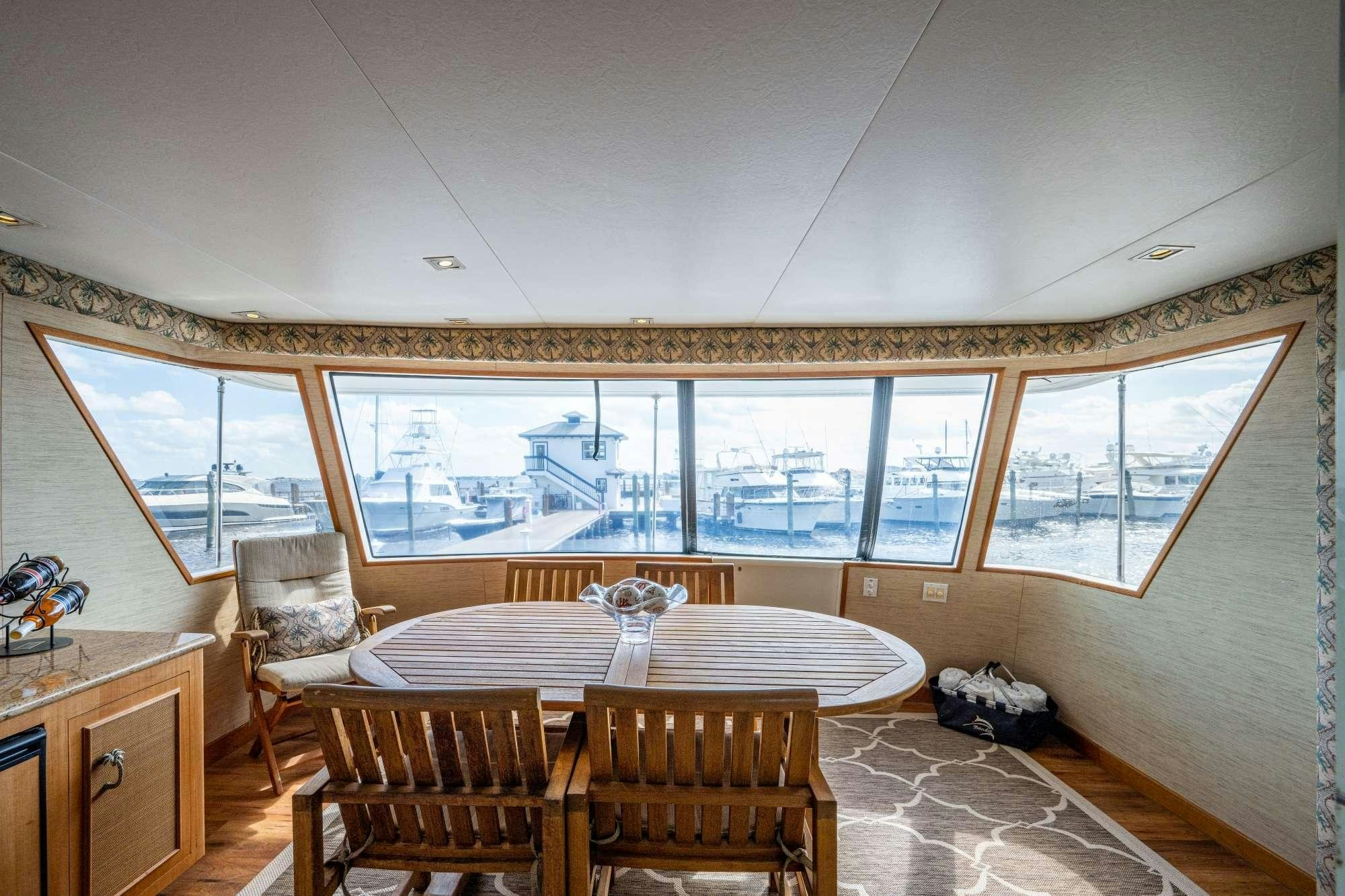 a dining table and chairs in a room with a large window aboard BANDIT Yacht for Charter