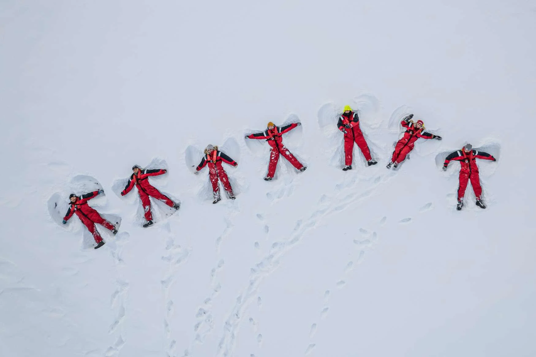 a group of people in red climbing a snowy mountain aboard ARGUS Yacht for Charter