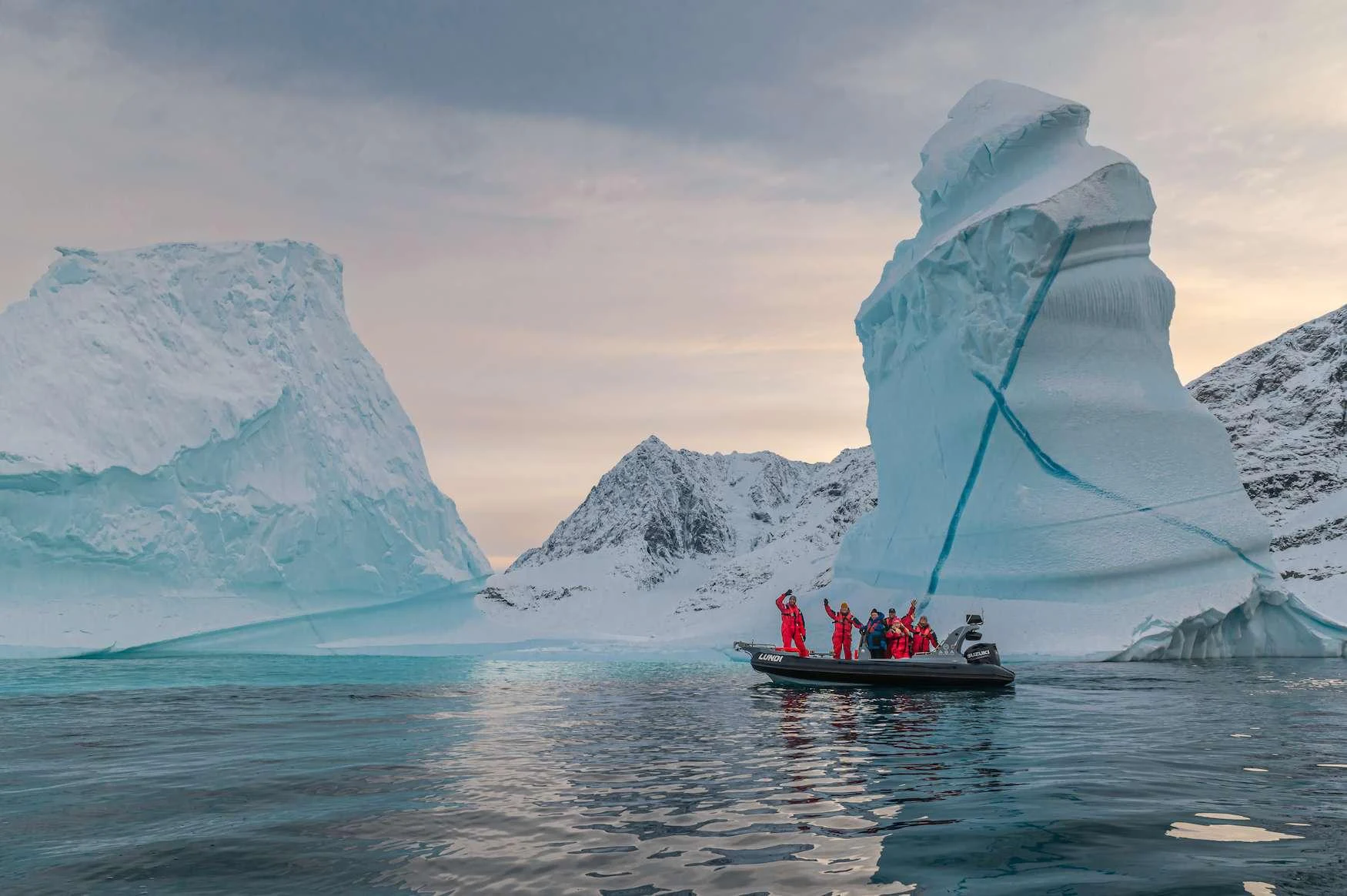 a boat in the water with a large iceberg in the background aboard ARGUS Yacht for Charter