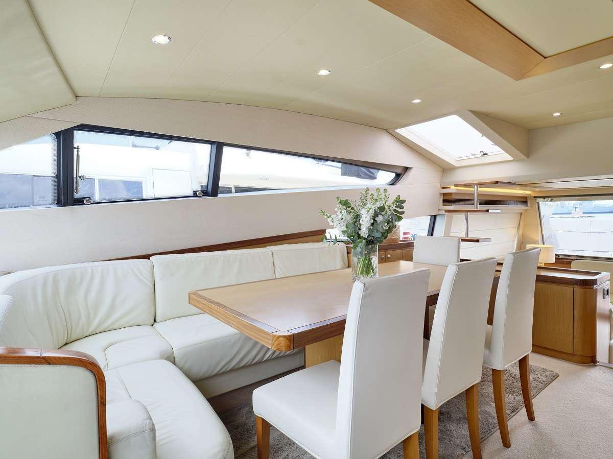 a room with white chairs and a table with a vase of flowers on it aboard FLOW Yacht for Charter