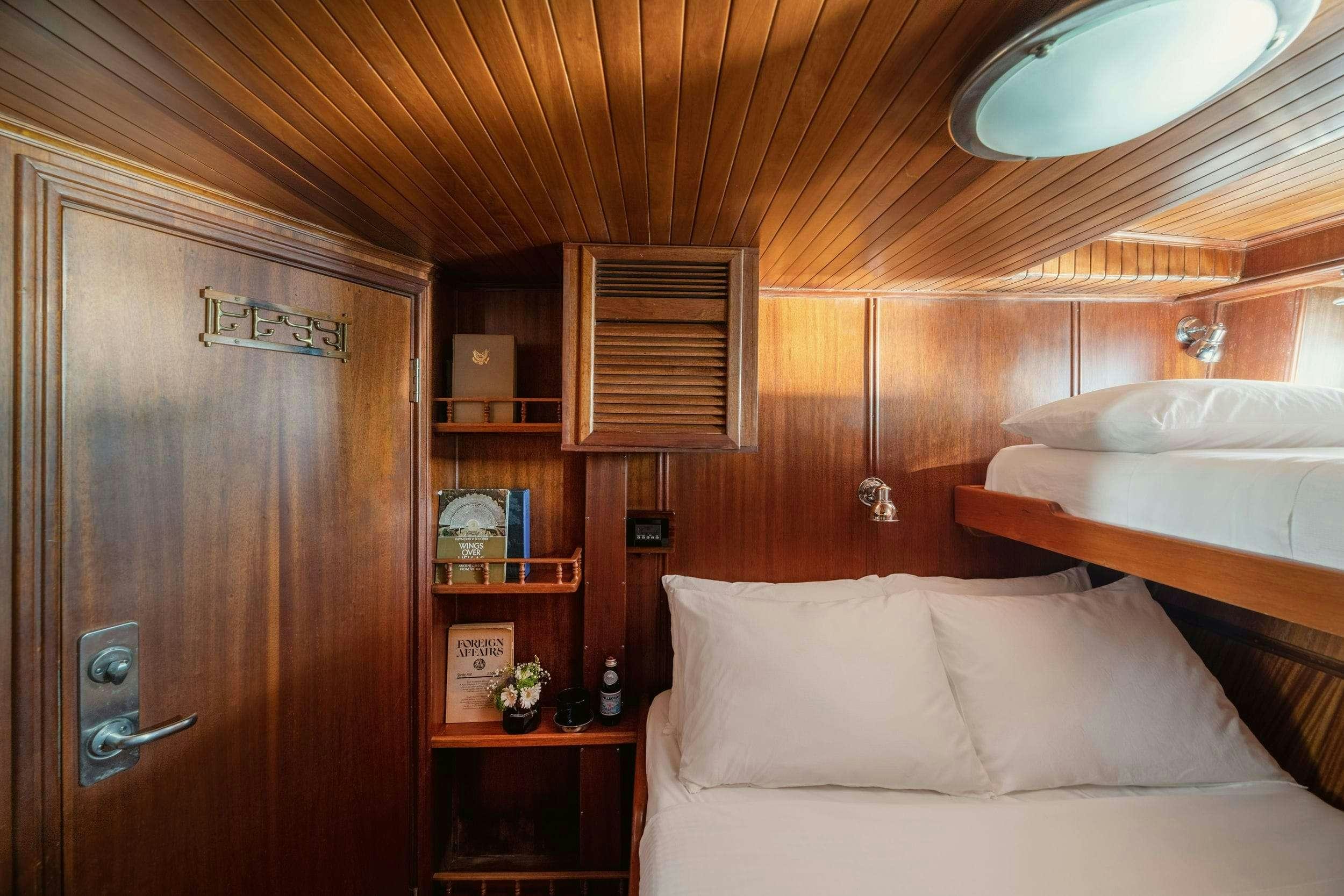 a room with a bed and a bookcase aboard LITHI Yacht for Charter