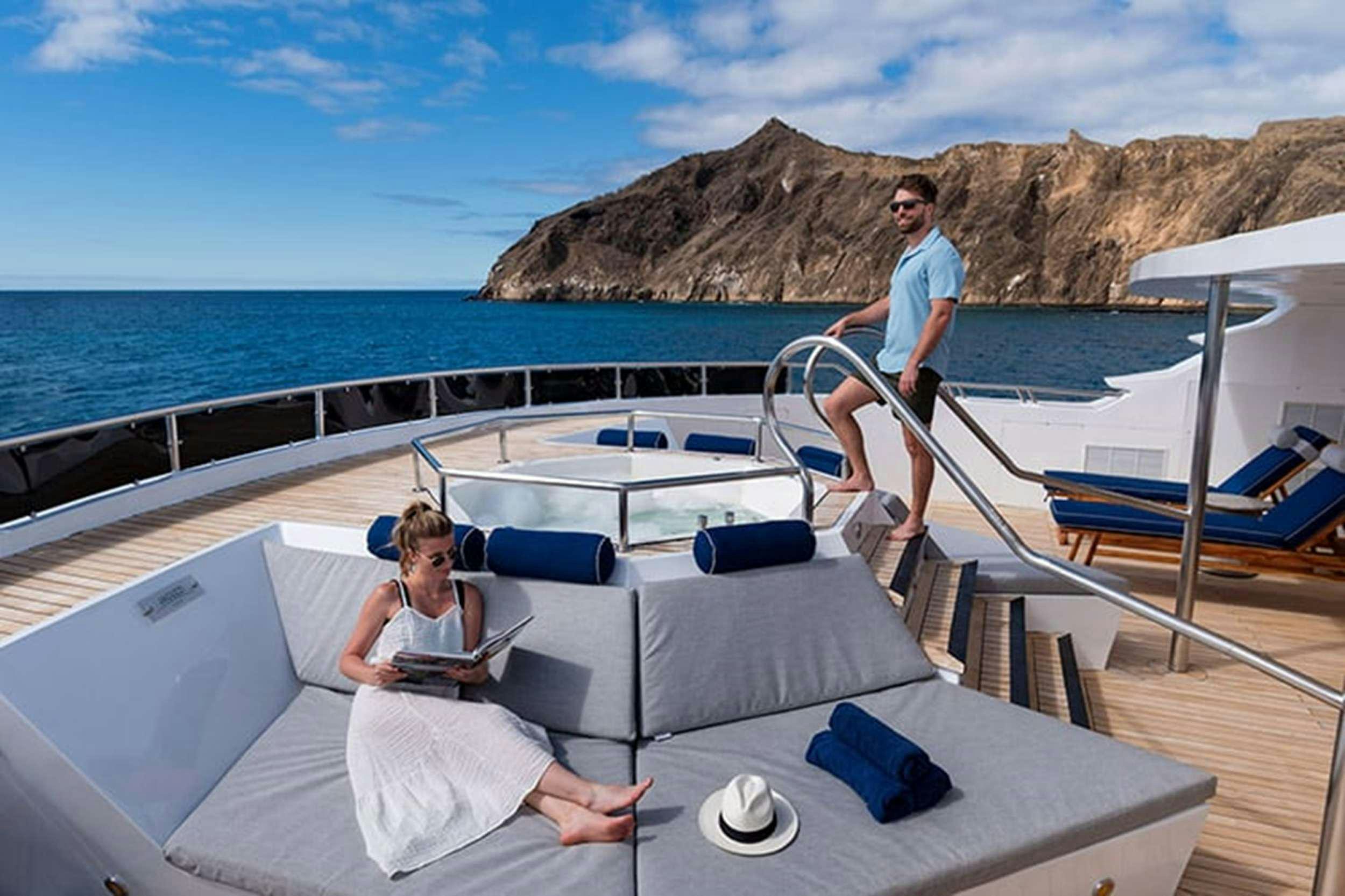 a man and a woman sitting on a boat on the water aboard GALAPAGOS HORIZON Yacht for Charter