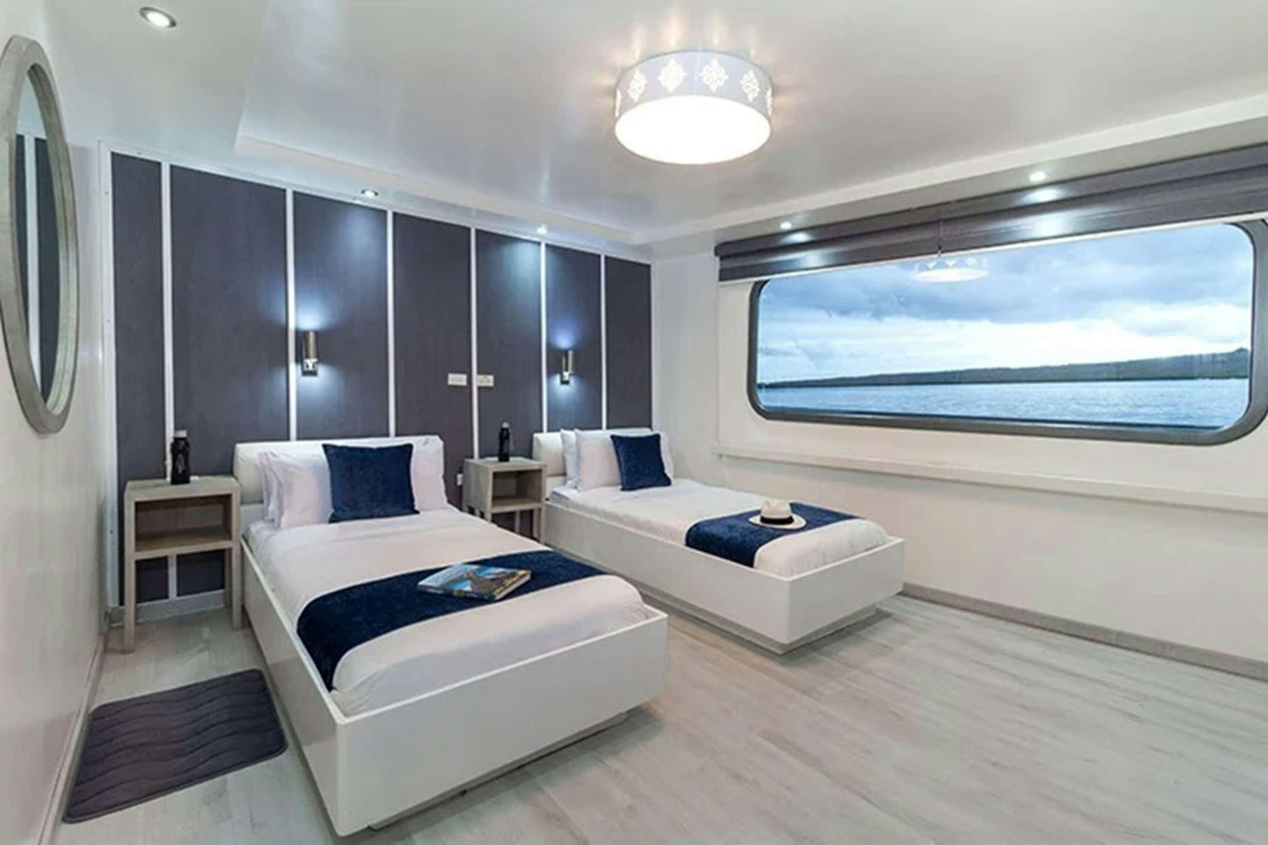 a room with a bed and a window aboard GALAPAGOS HORIZON Yacht for Charter